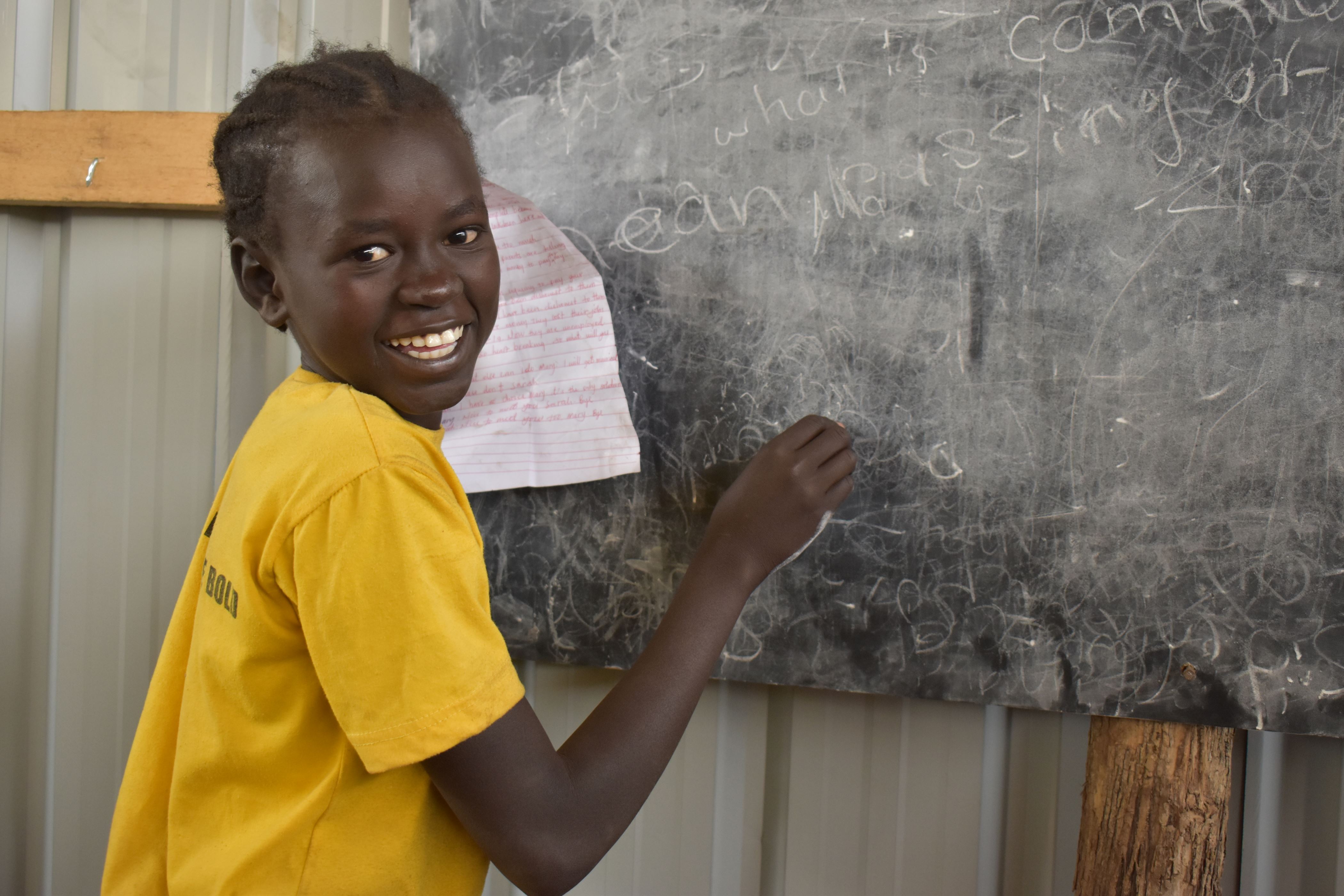 Yar a 14-year-old P.4 pupil in a classroom writing down questions for her friends on the chalkboard.