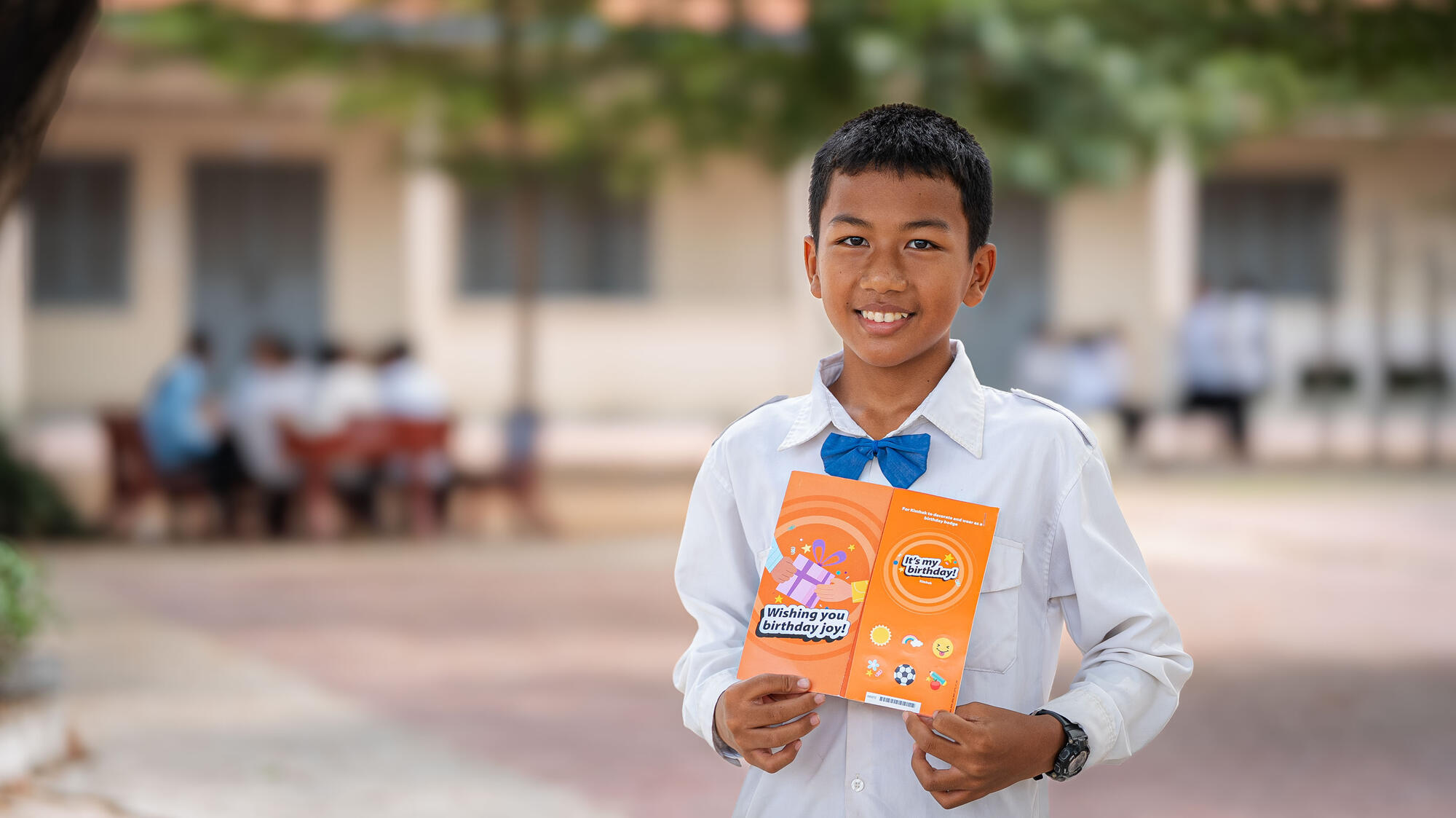 A young boy from Cambodia holding up his birthday card from his child sponsor