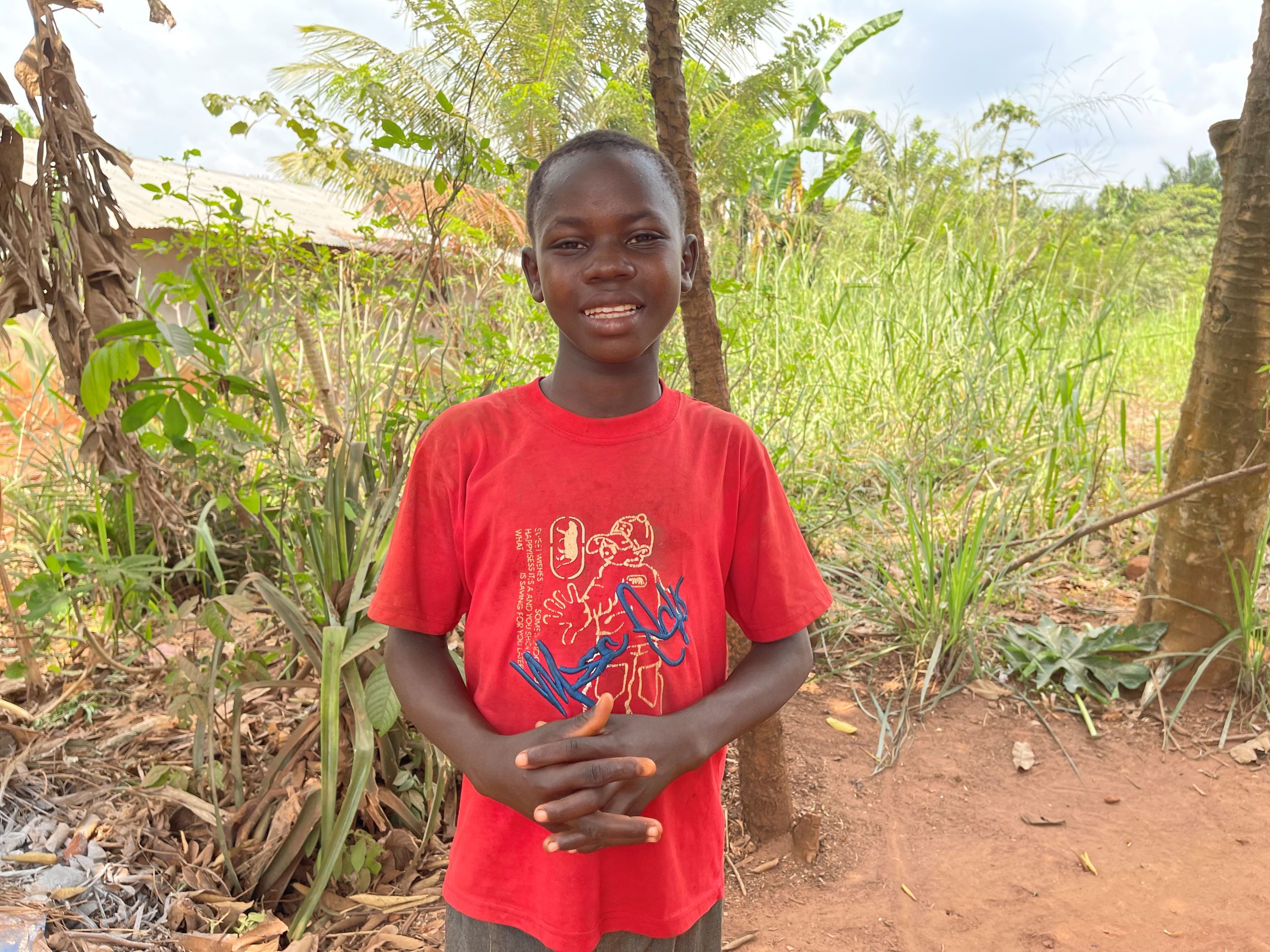 Smiling boy from DRC wearing a bright red t-shirt