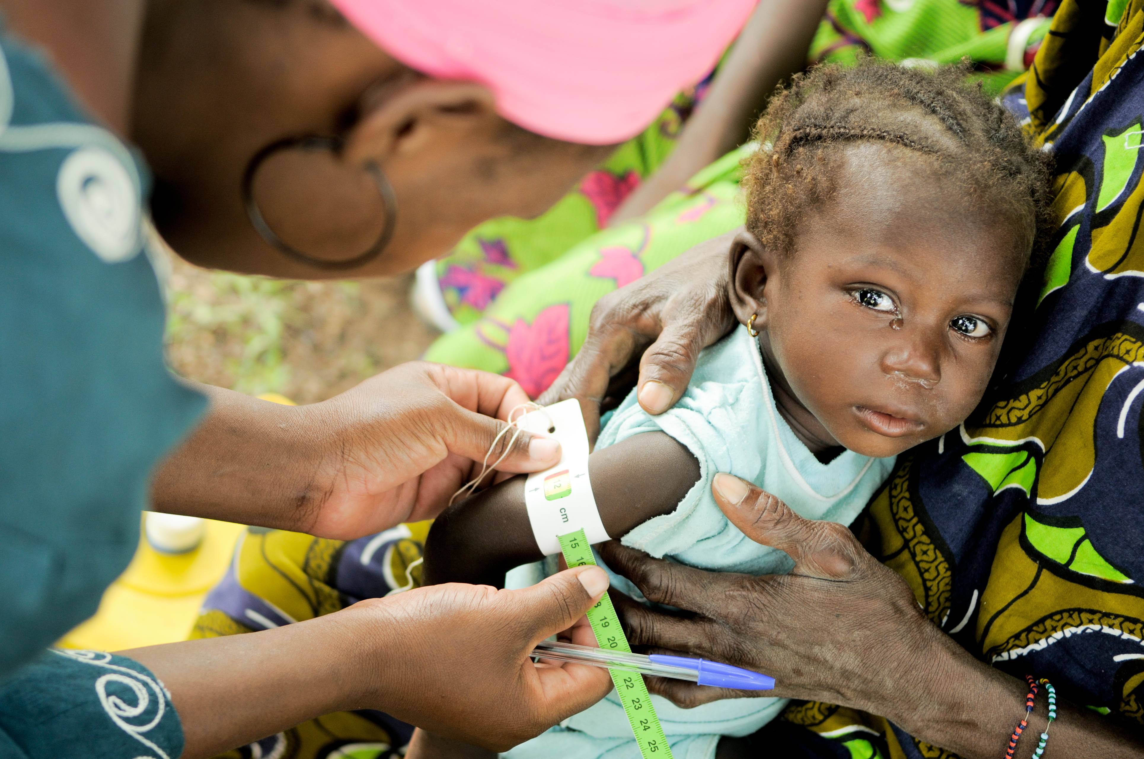 A young child has their upper arm measured to check for signs of malnutrition