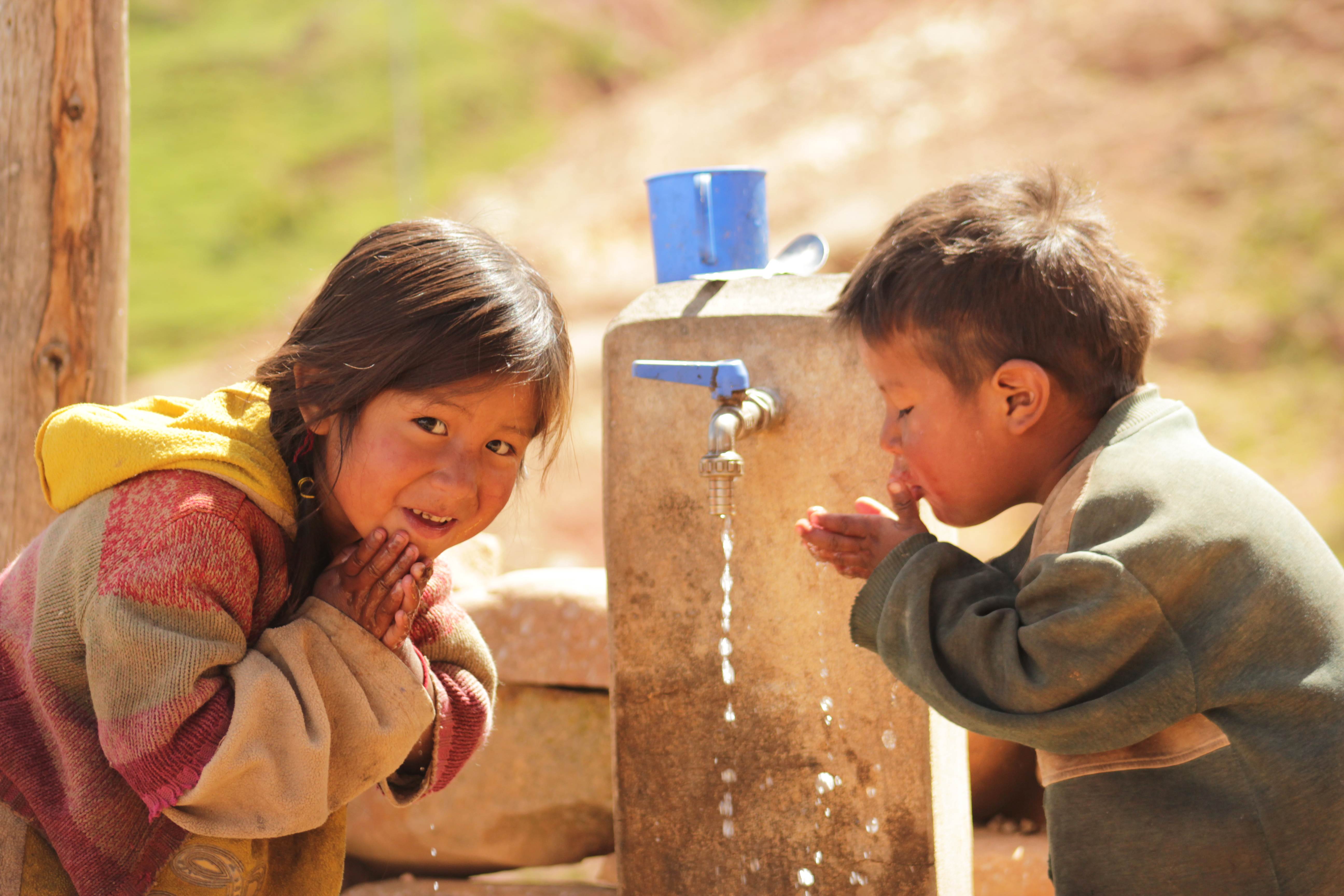 Boy and girl from Bolivia collect water from a clean drinking water tap