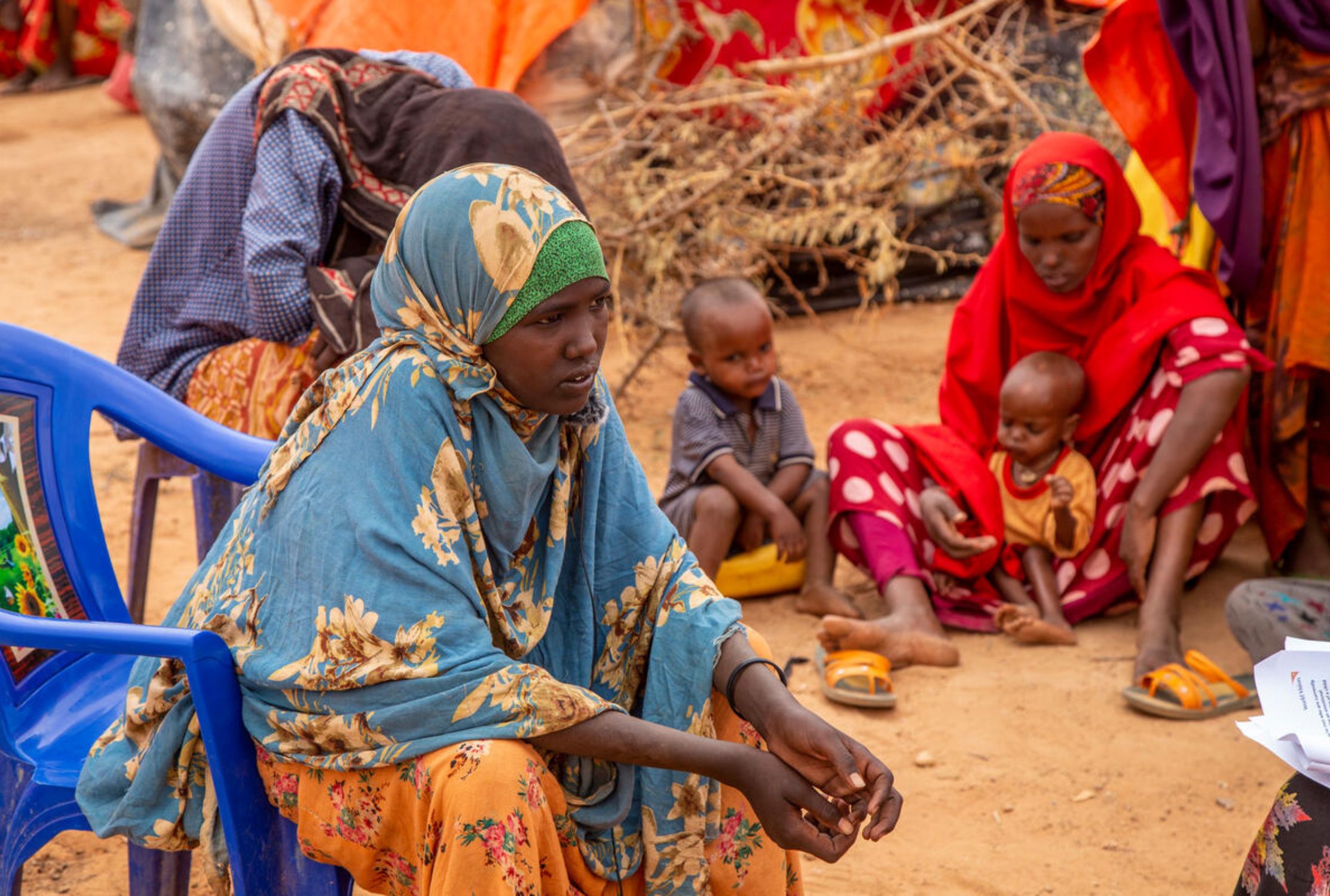Girl sits in front of her family and a makeshift settlement in Somalia