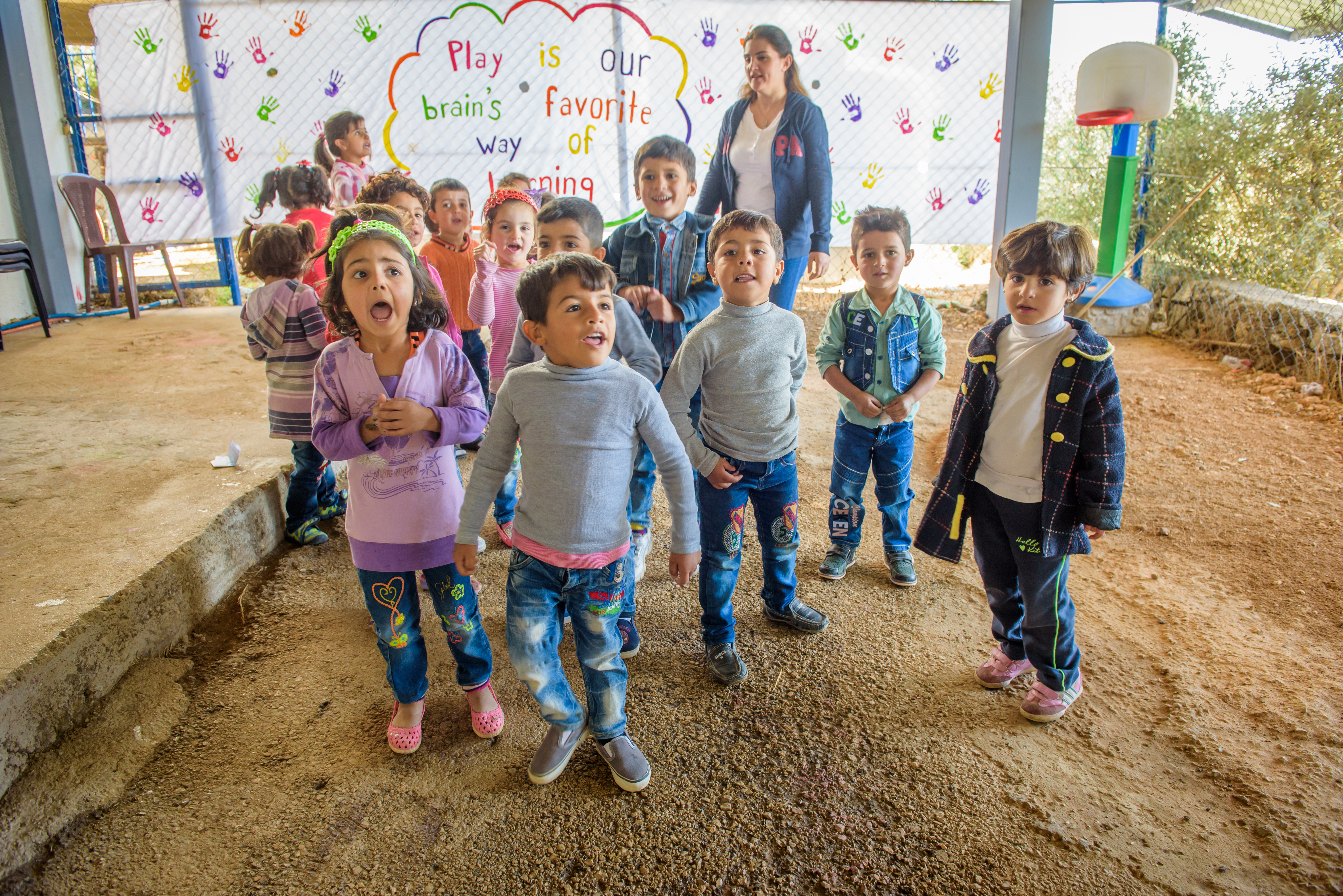 Group of children in Lebanon jump around in a classroom