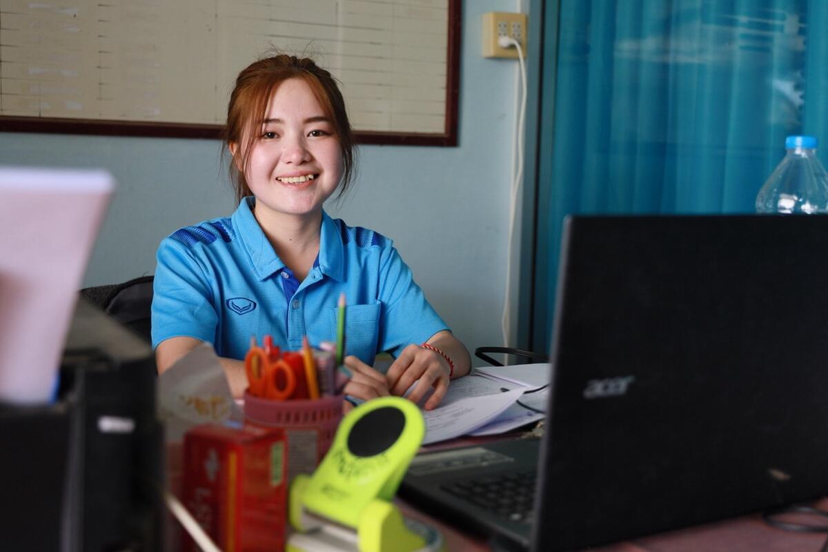 Former sponsored girl in an office, smiling.