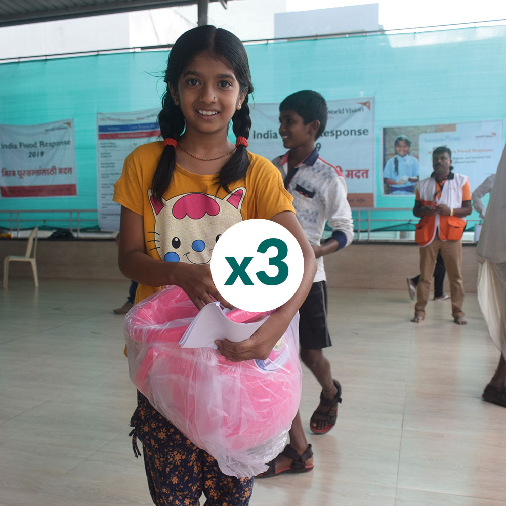 A girl from India holding a sanitary kit containing sanitary pads, underwear, water, and soap 