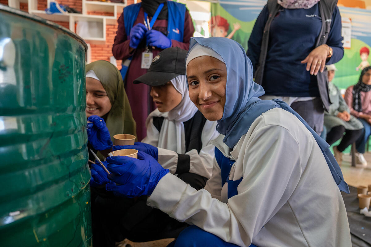 A young girl wearing blue gloves poses for a photo in the middle of a group project