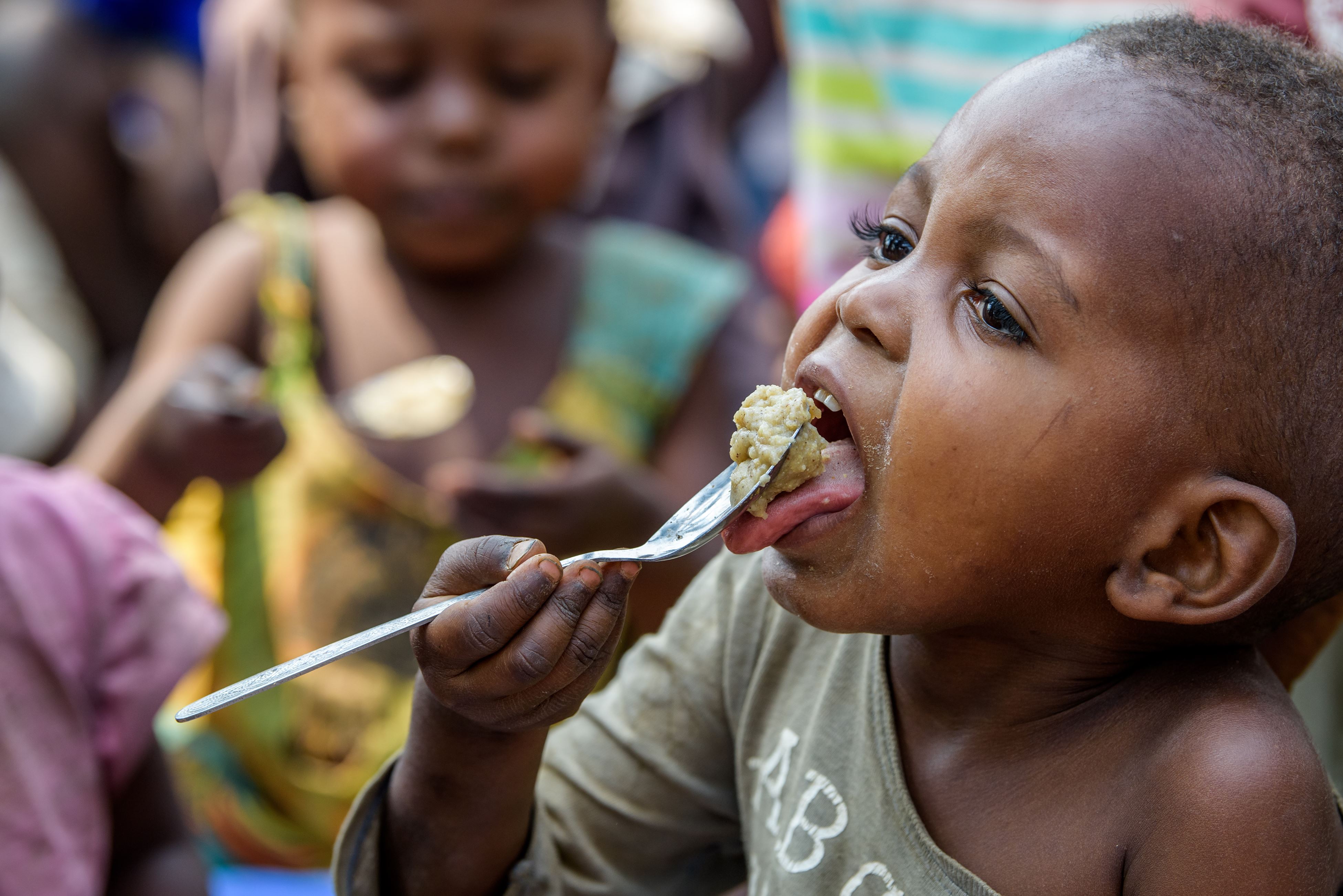 A child hungrily eats porridge with a spoon
