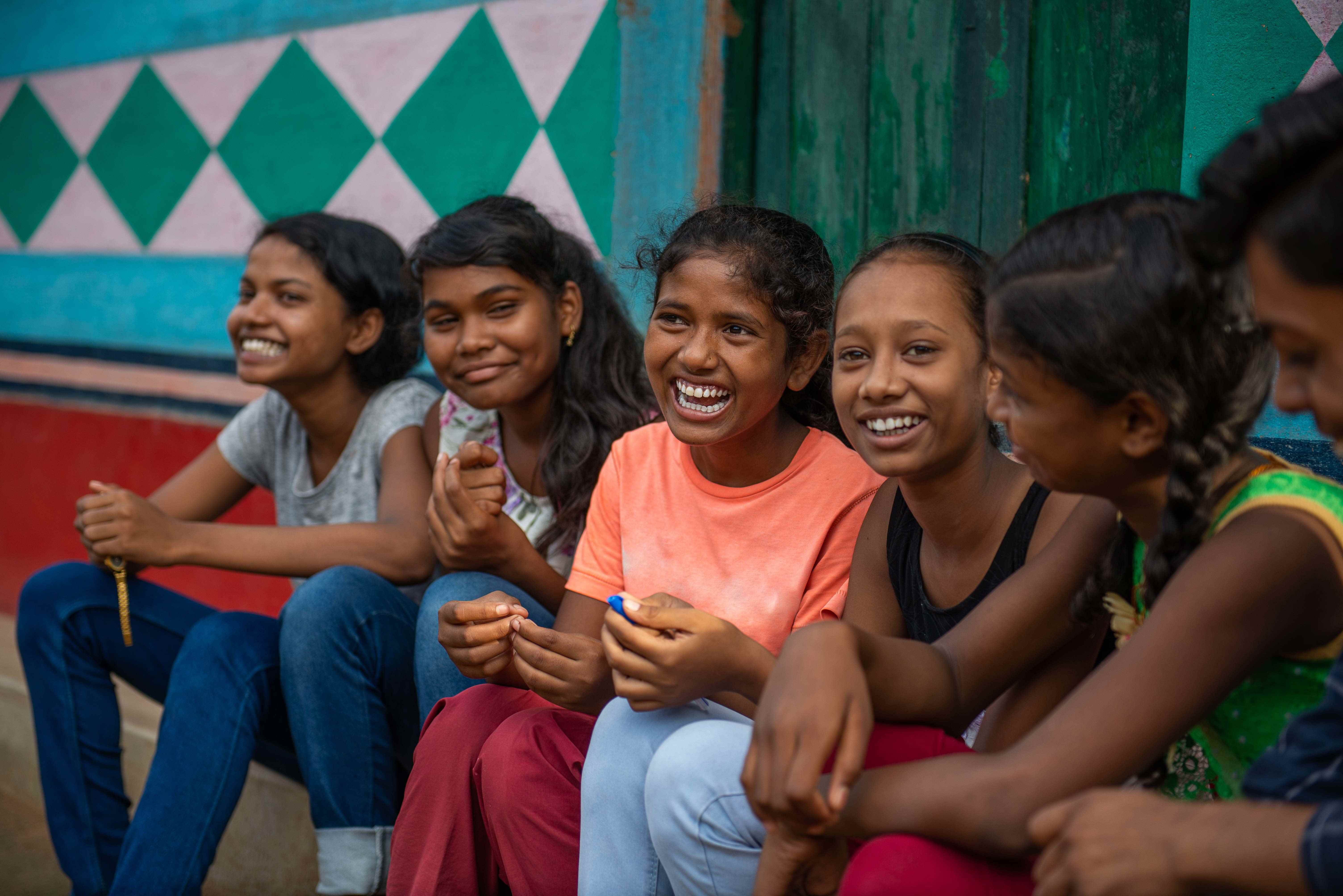 A group of girls in India sit together and smile, having received a good education