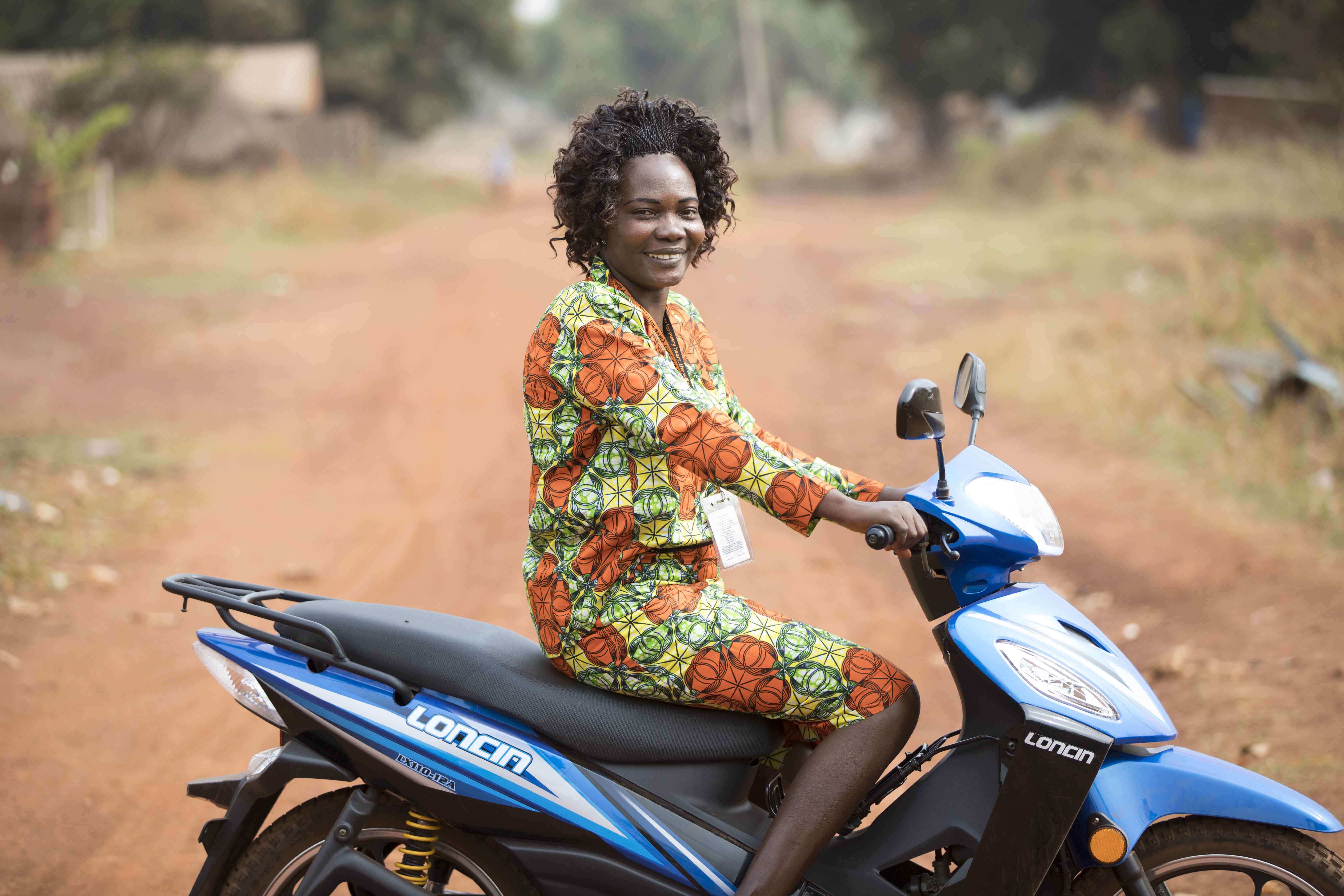 World Vision aid worker in South Sudan sits atop a motorbike on a dirt road