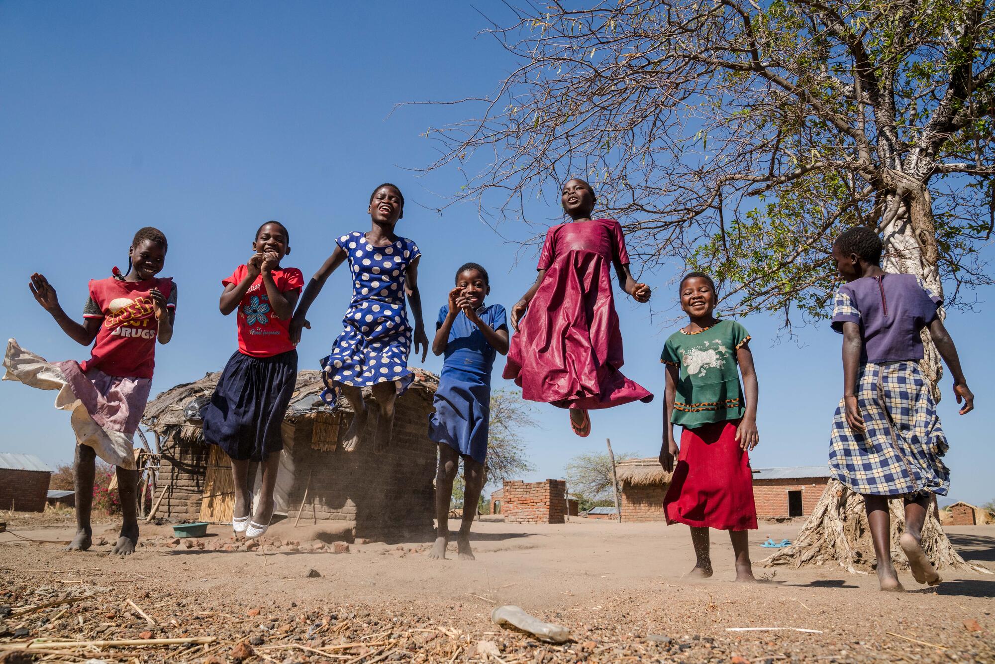A group of children in Malawi jump in the air having fun
