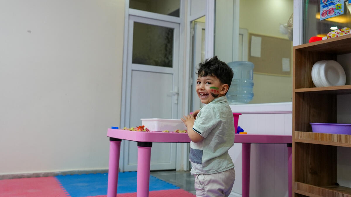Smiling little boy with  paint on his face, playing in a Child Friendly Space, Turkey.