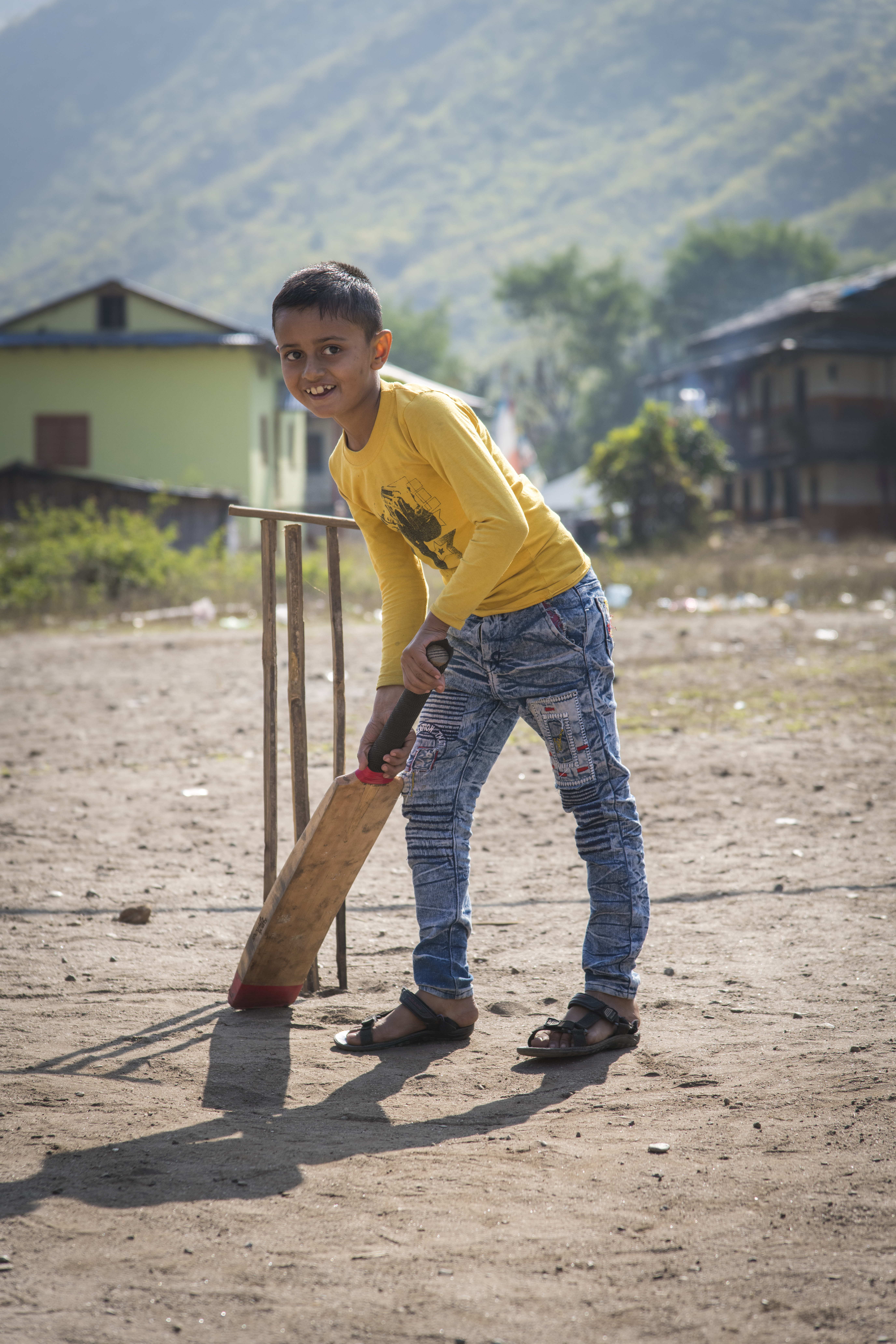 A boy stands with cricket bat, in front of the stumps, ready to play cricket
