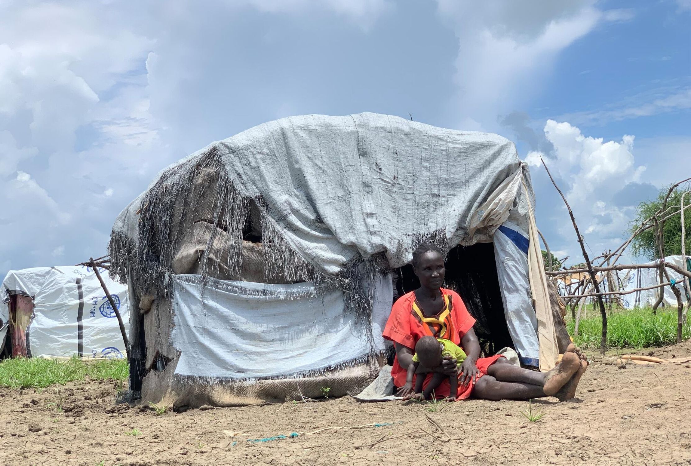 Aluel sits outside a makeshift home with her child in South Sudan