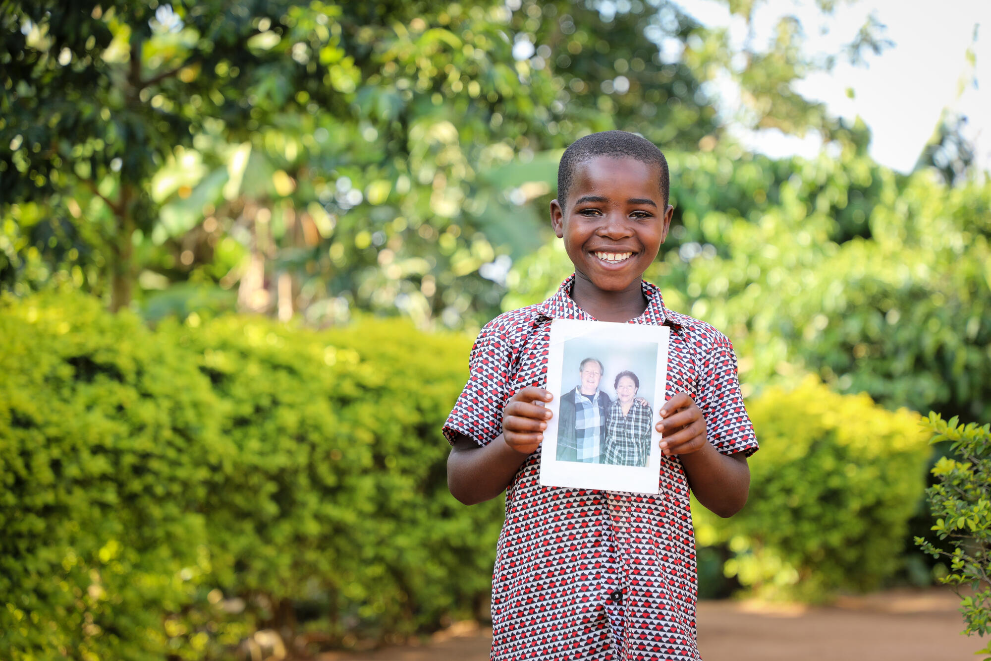 Victor from Uganda smiles and holds up a photo of the sponsor he chose