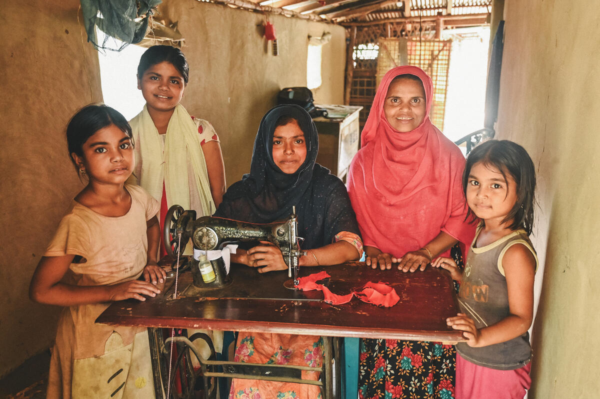Parvin and her family smiling around her sewing machine provided by World Vision, Bangladesh