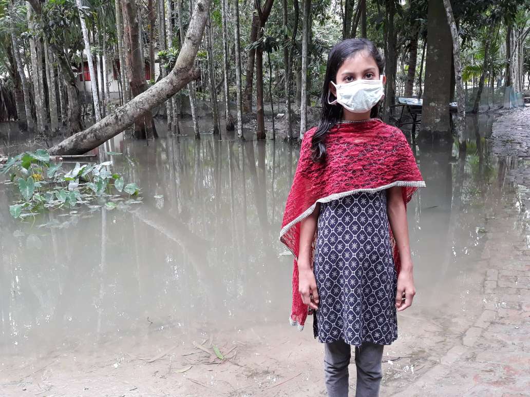 Girl in Bangladesh stands in the midst of floods where her village used to be