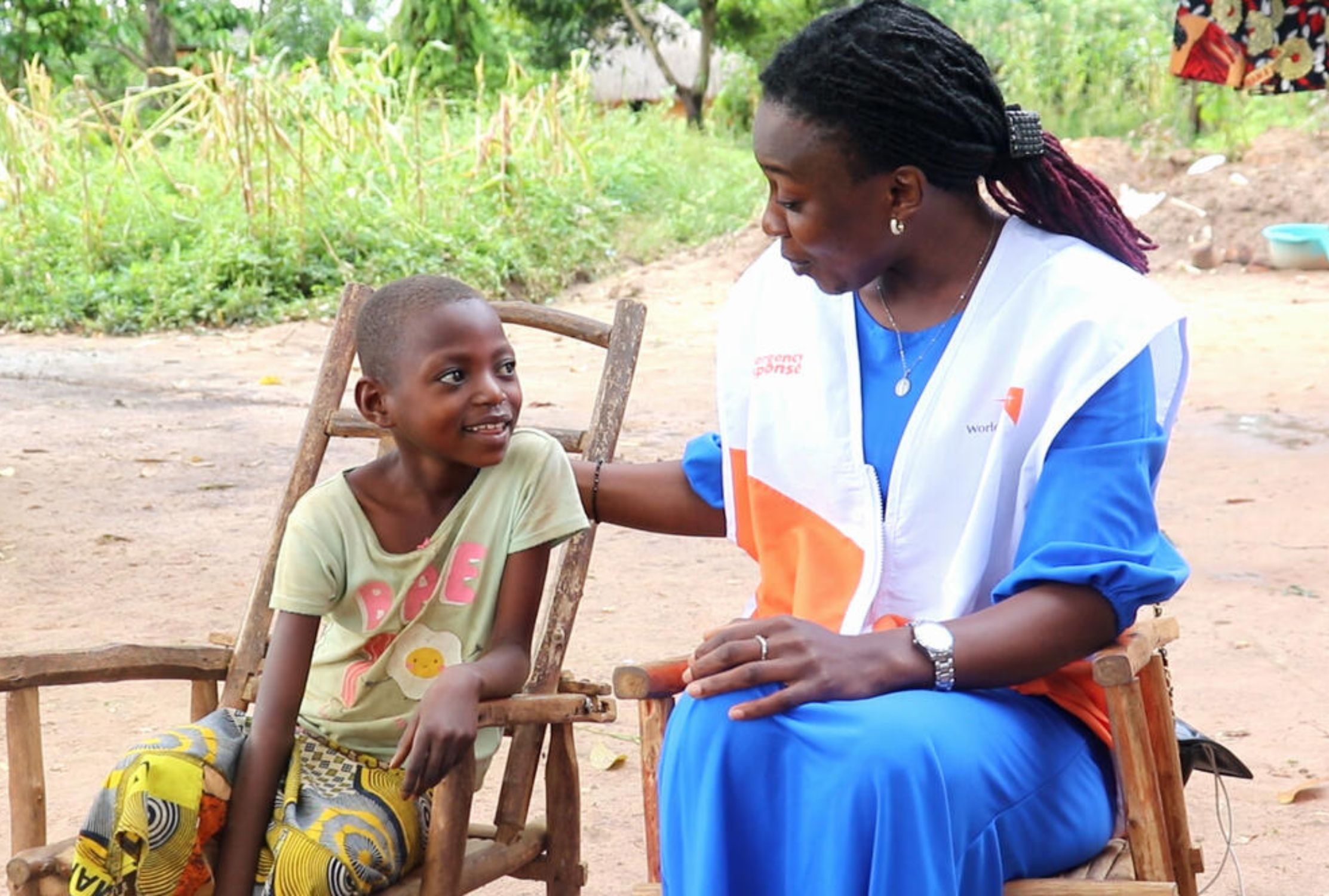 World Vision protection officer talks to a smiling child from DRC