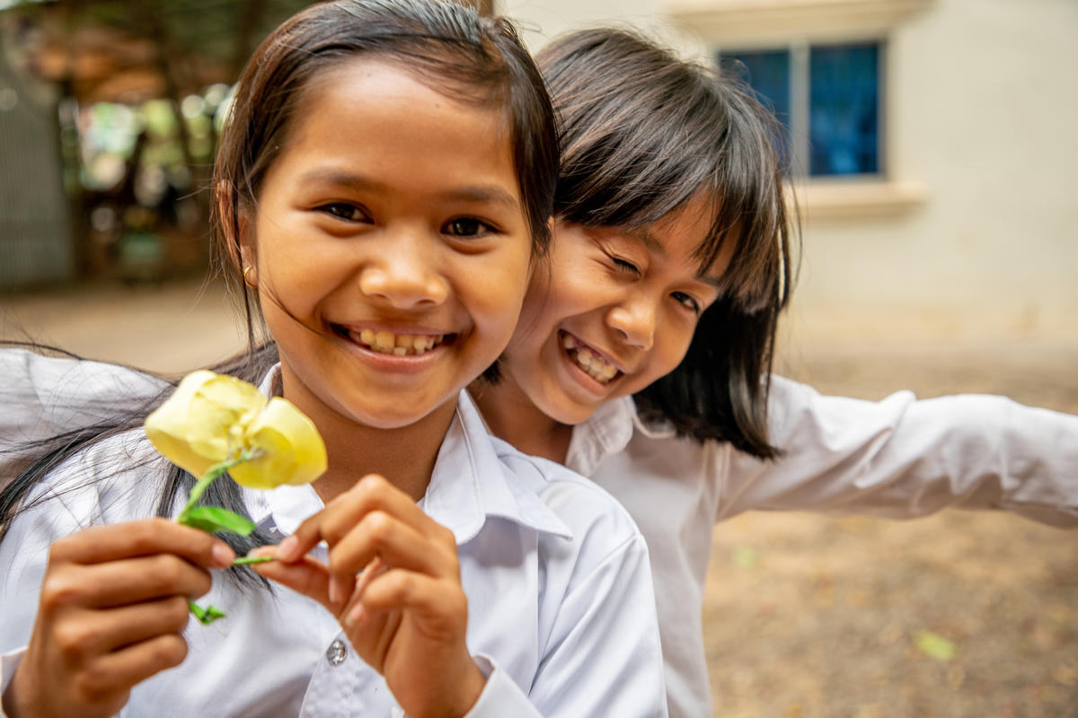 Two Cambodian girls grin widely as they play
