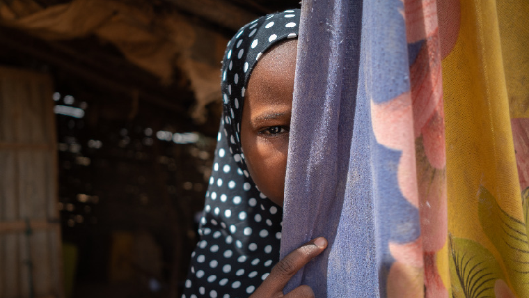 Fatima peeks out from the side of a curtain as she talks about child marriage