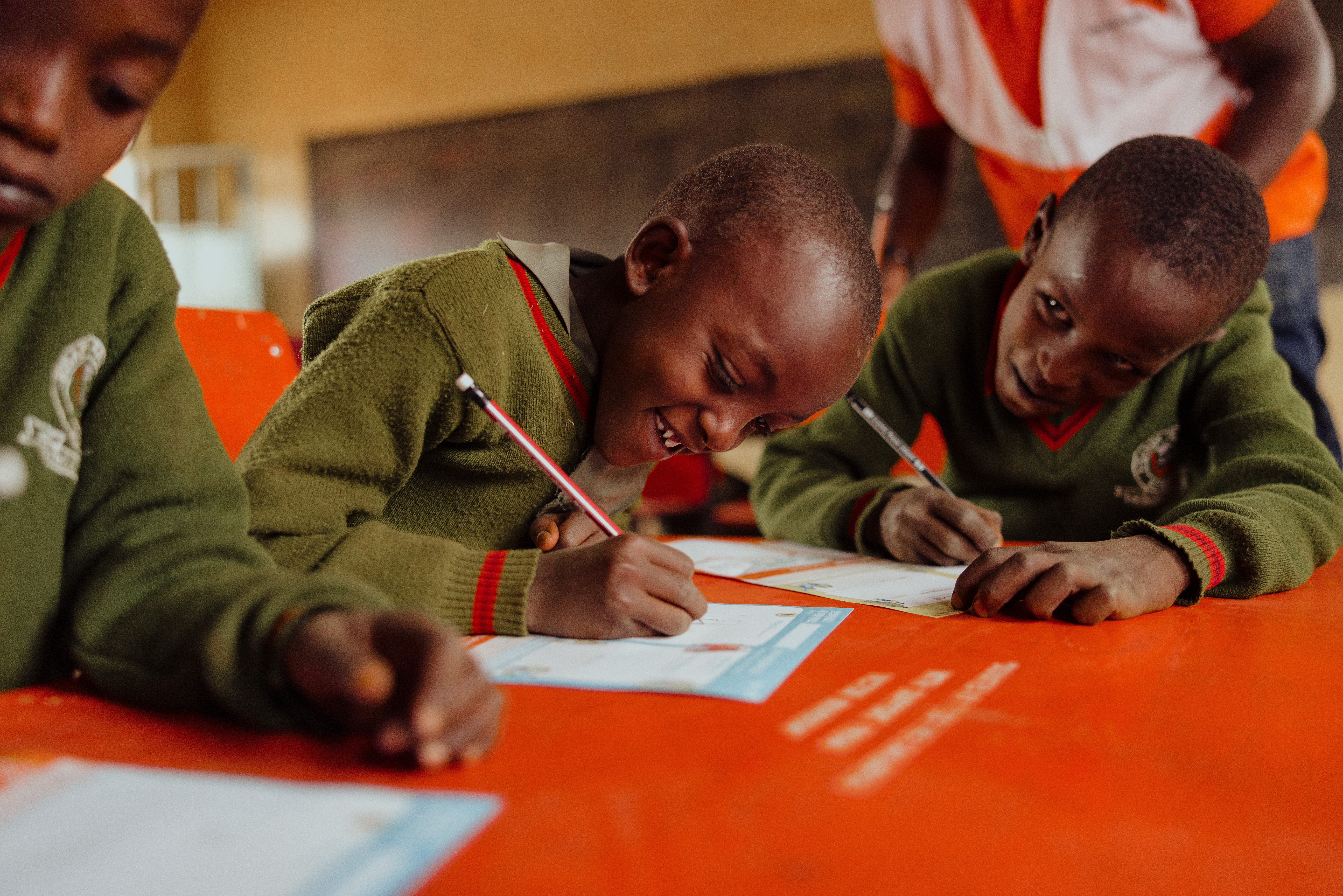 Children in Kenya writing about themselves, to send to their sponsors