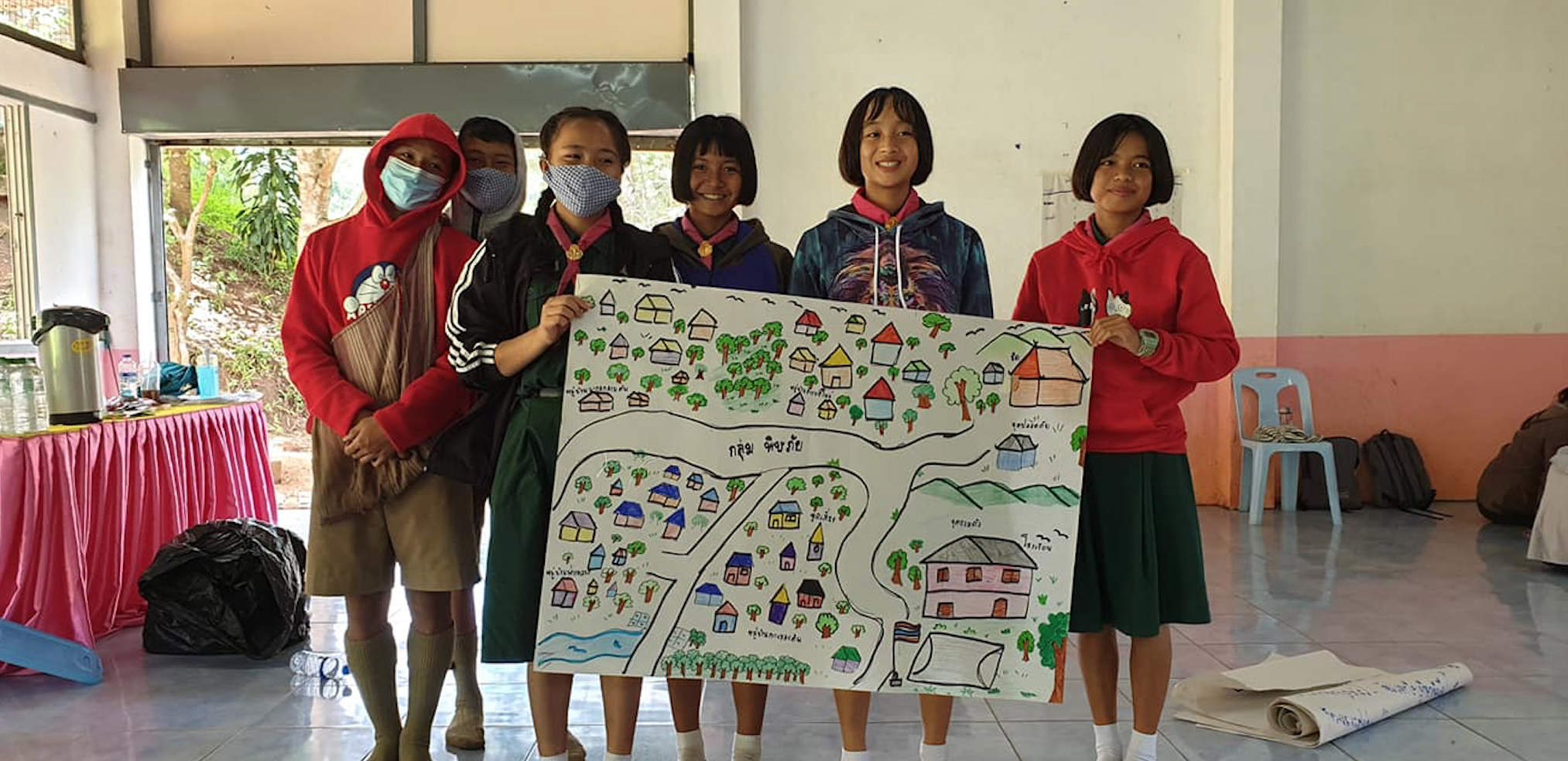 Группа в Таиланде держит плакат с разработанным ими планом действий на случай стихийных бедствий.