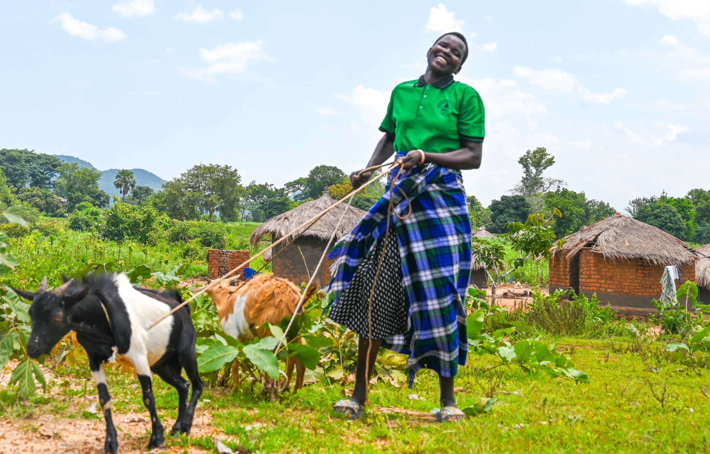 Woman in Uganda enjoying looking after her goat
