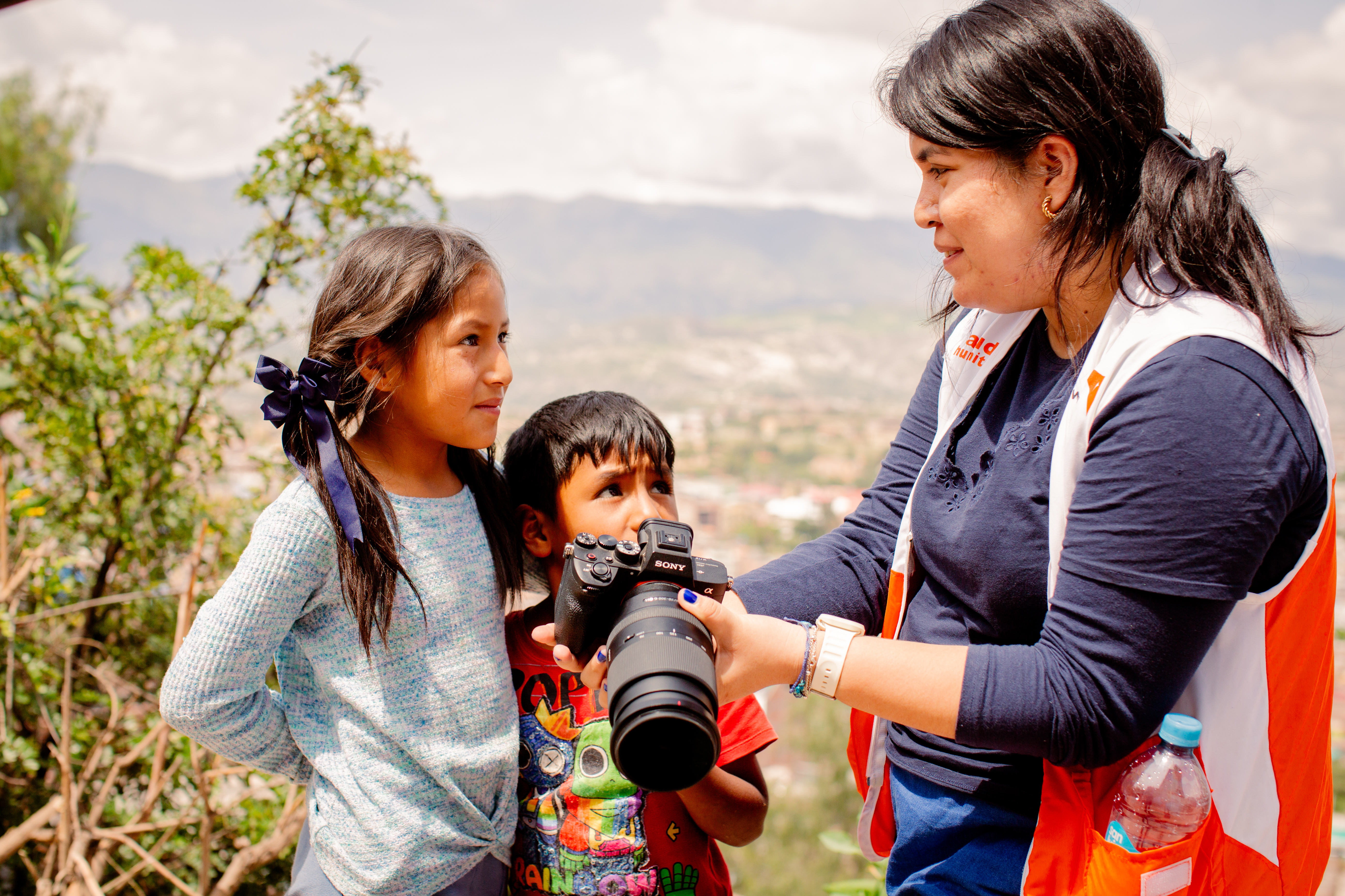 Two children being shown their photos by a World Vision staff member in Peruographs on a camera