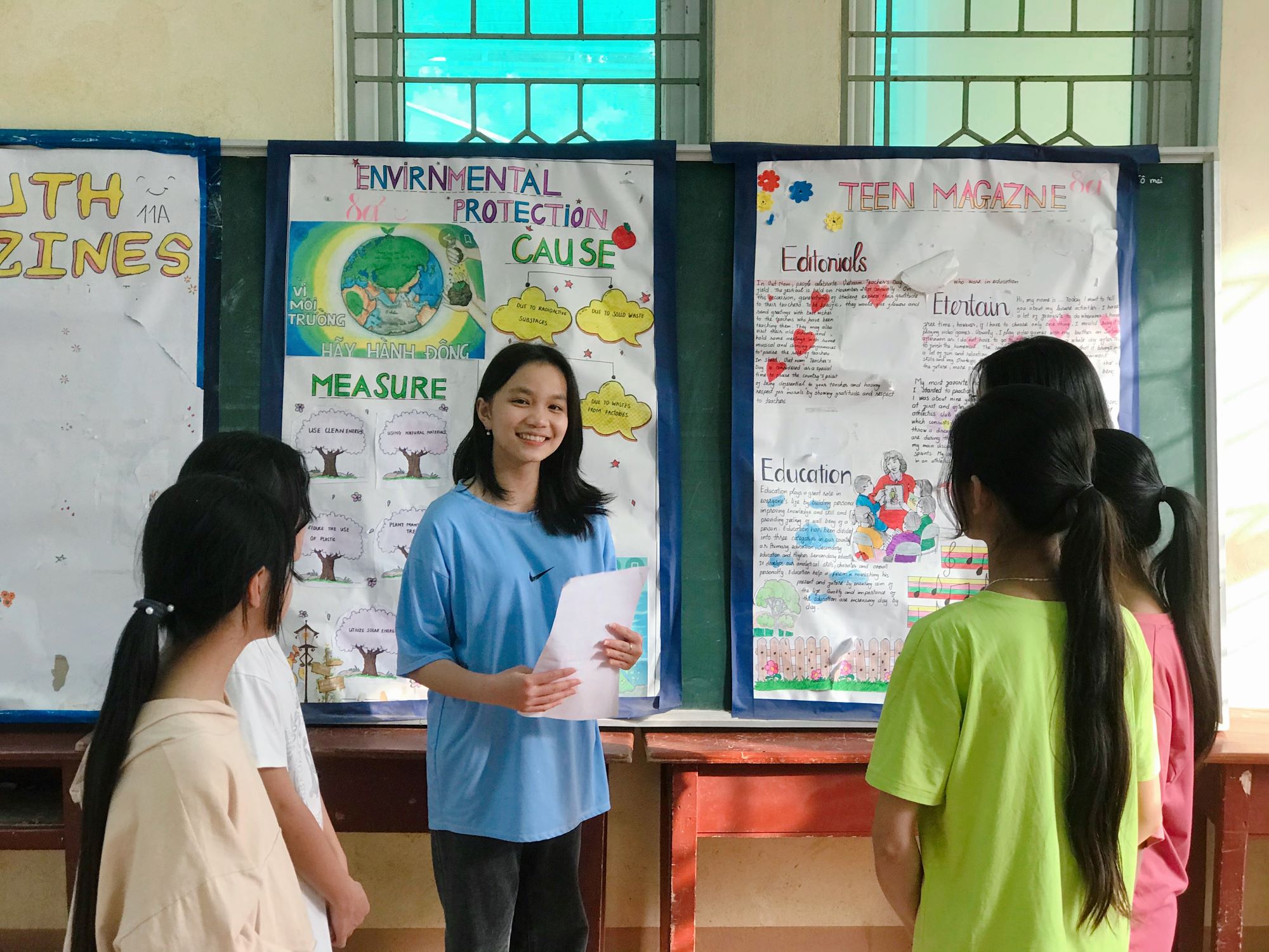 Girl from Vietnam smiles broadly in front of her peers and a display and educational information