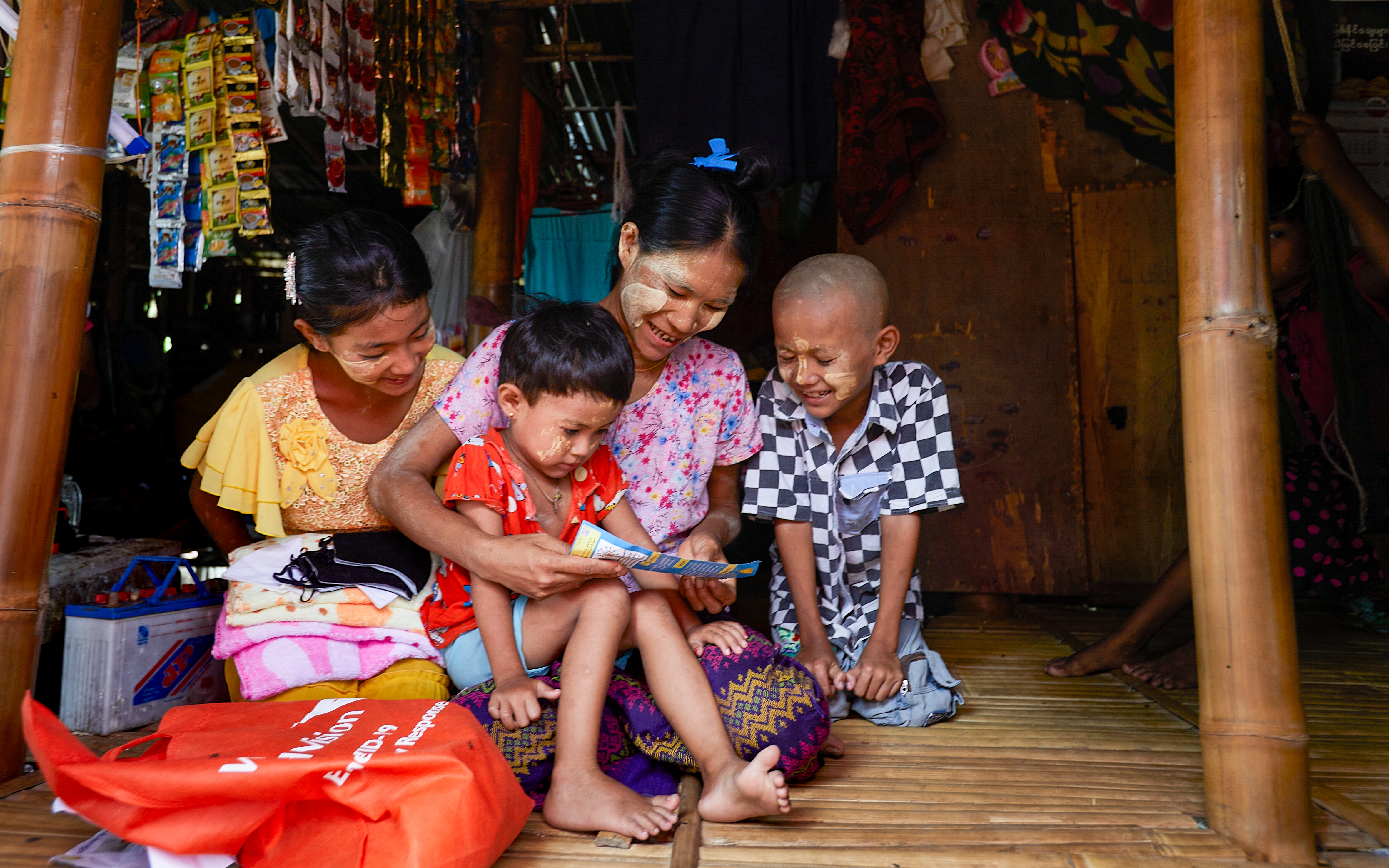 Women and children gather to read from a booklet in Myanmar