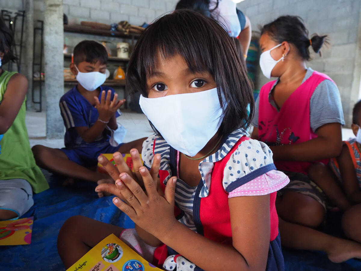 A young girl washes her hands with hand sanitiser. She's wearing a mask to protect from coronavirus.