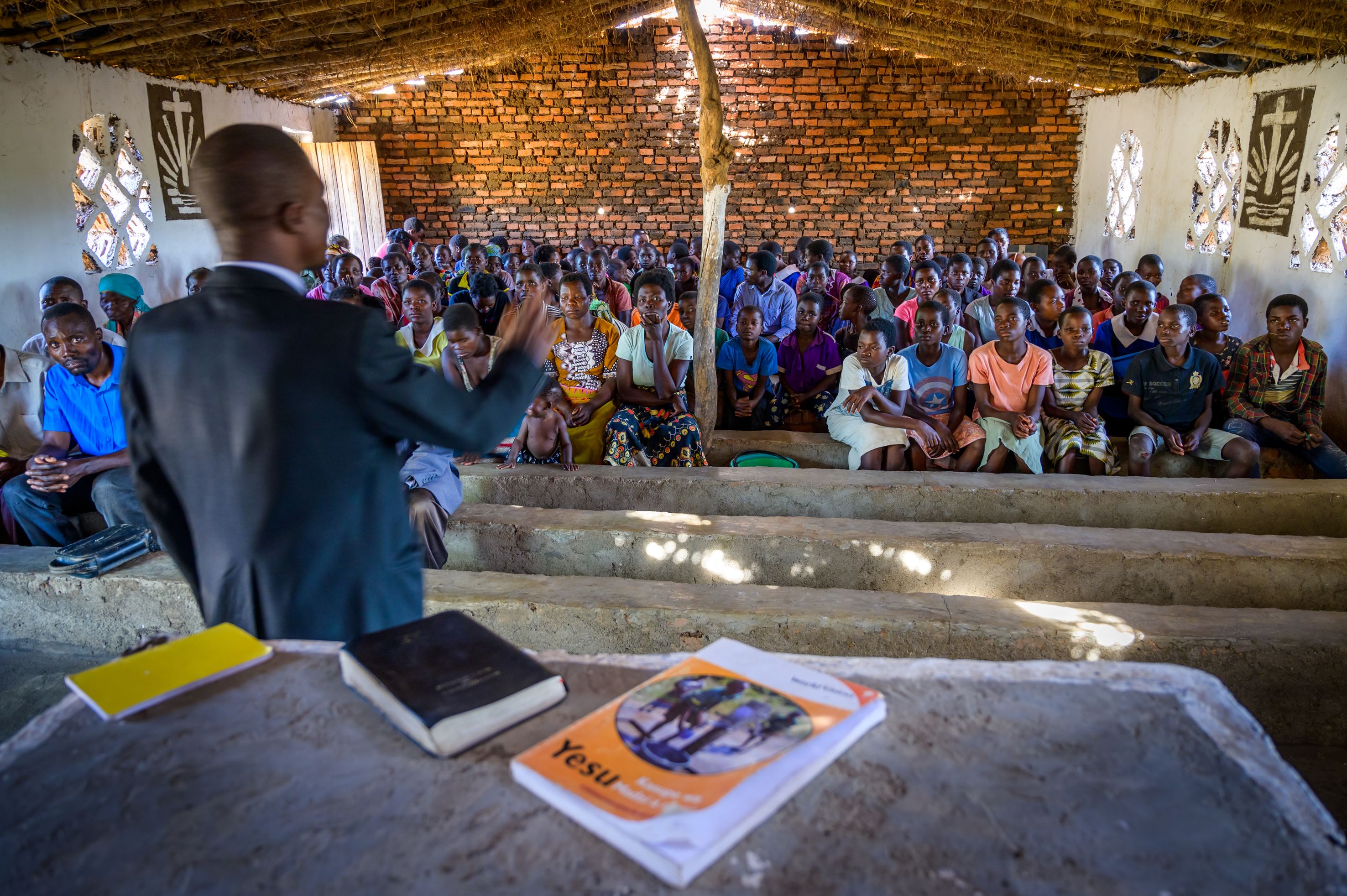 A youth group and congregation members listen to their pastor preach in Malawi