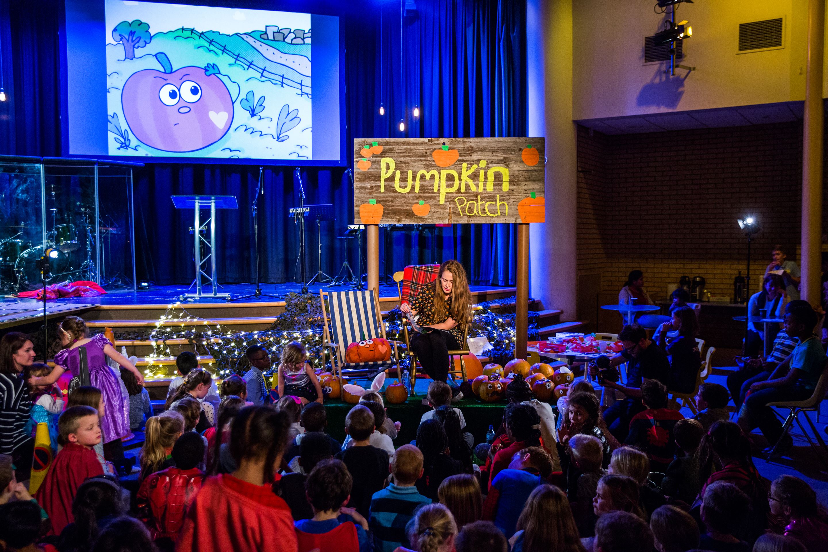 Children sit in a room in the UK being read a Patch the Pumpkin story