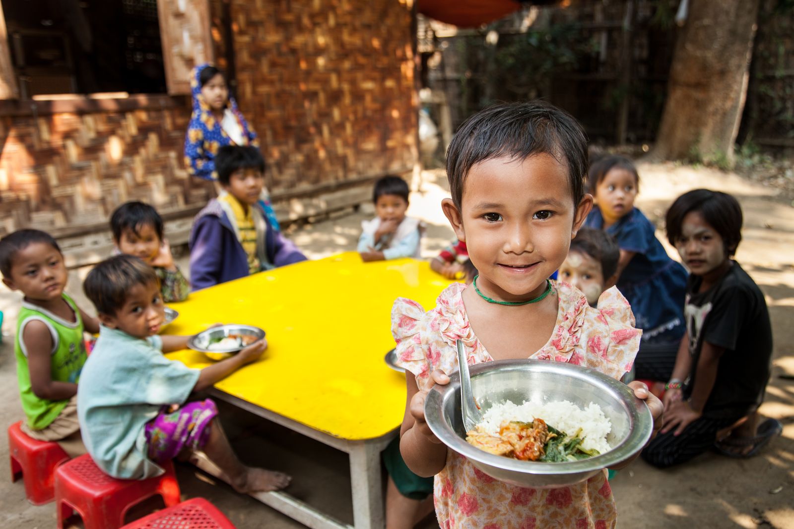 Young girls smiles at camera whilst holding a plate of food