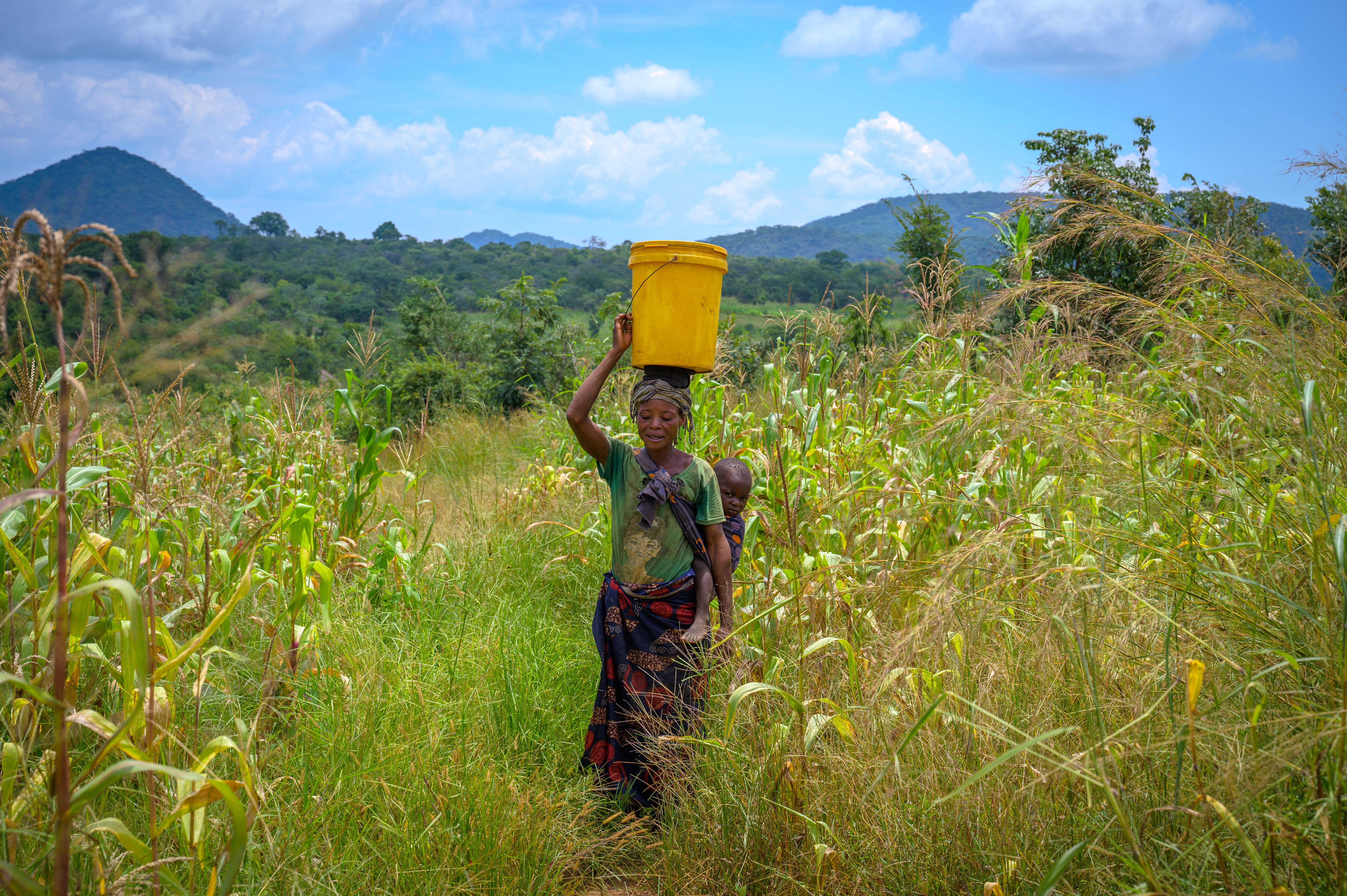 Mother and baby carry a bucket of water