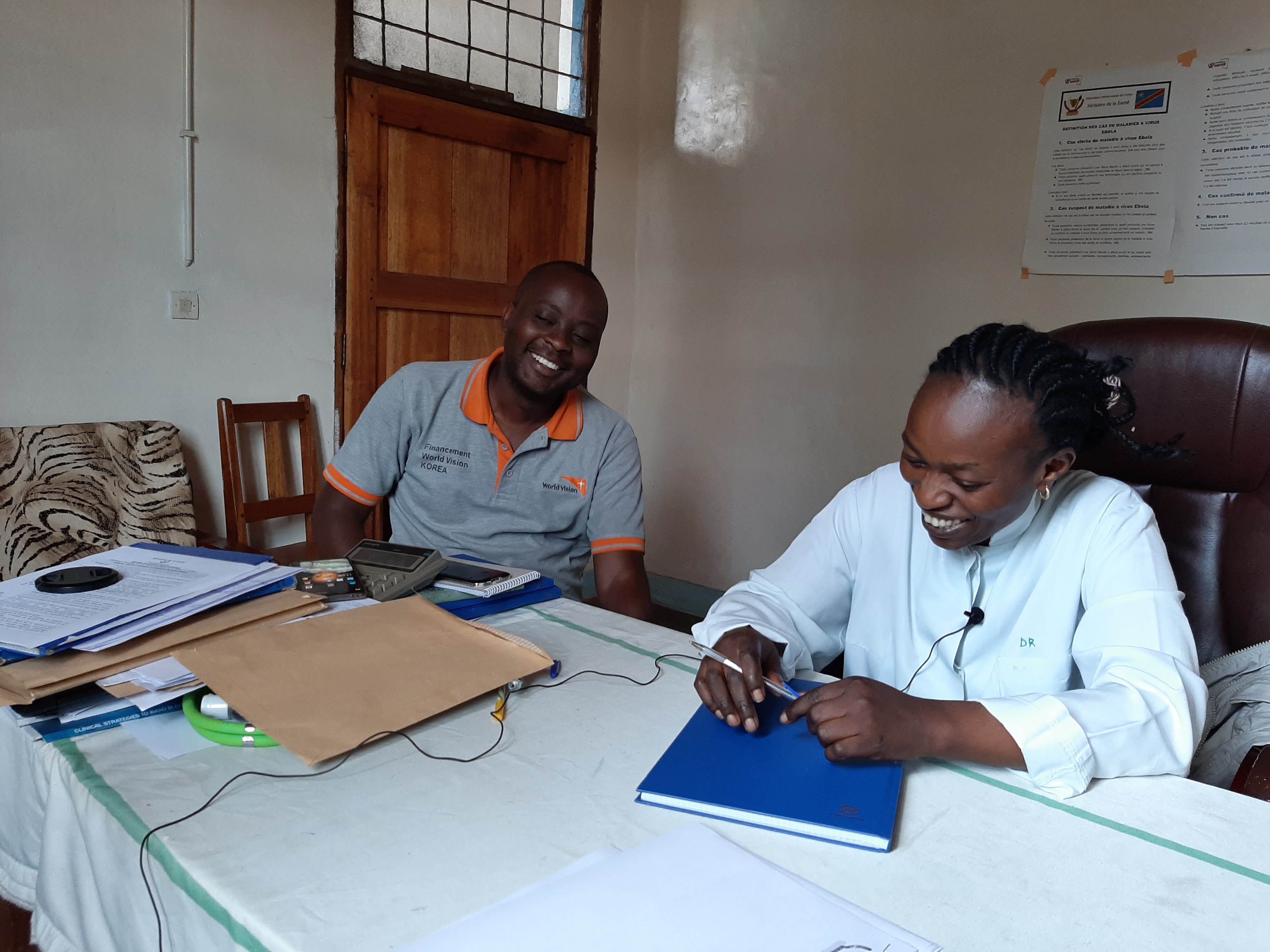World Vision Project Co-ordinator and a Senior Doctor in charge of the Binza hospital, sitting at a table, for discussions about the children in the area, the malnutrition programme and regional health centres.