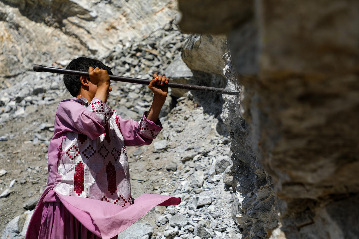 A young child digs with a shovel in a mine. 