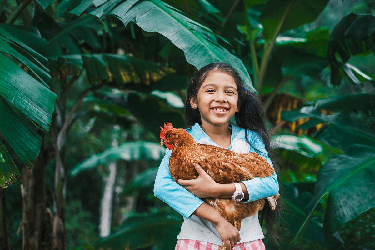 Young girl from Honduras hugging her chicken charity gift