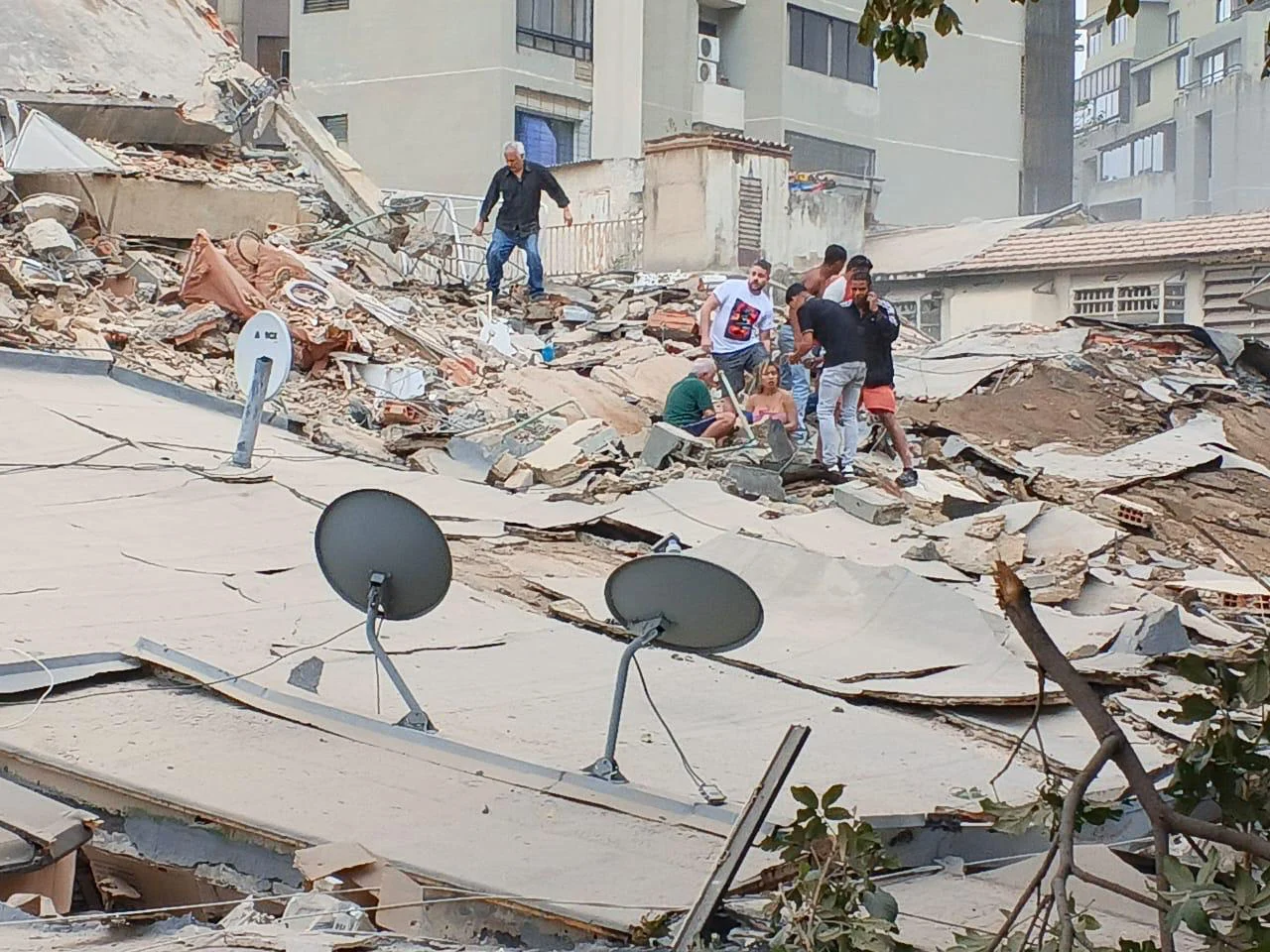 People search for survivors amongst collapsed buildings
