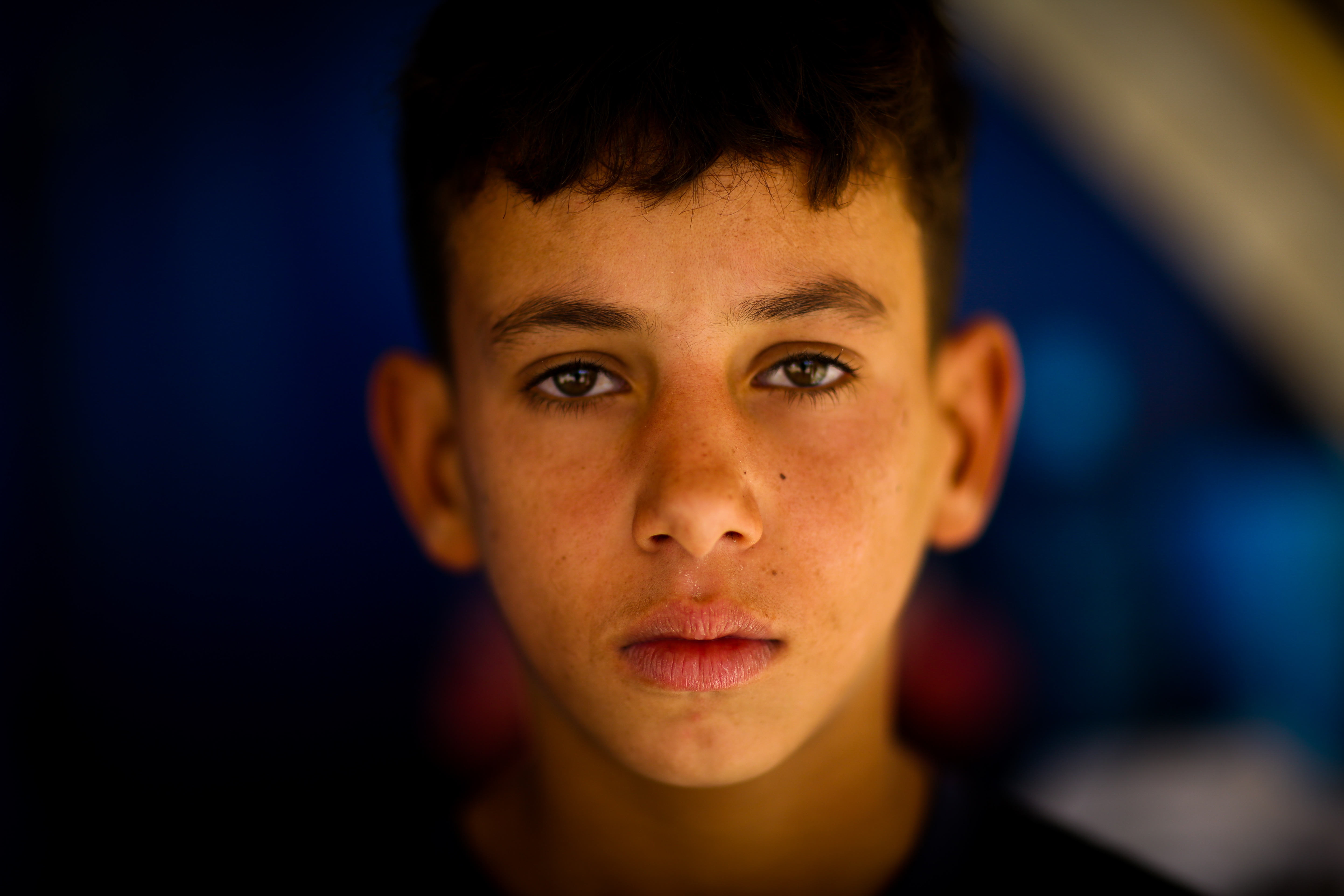Boy age 12 looks older than his years, living in tented settlement in Iraq having fled bombs and persecution