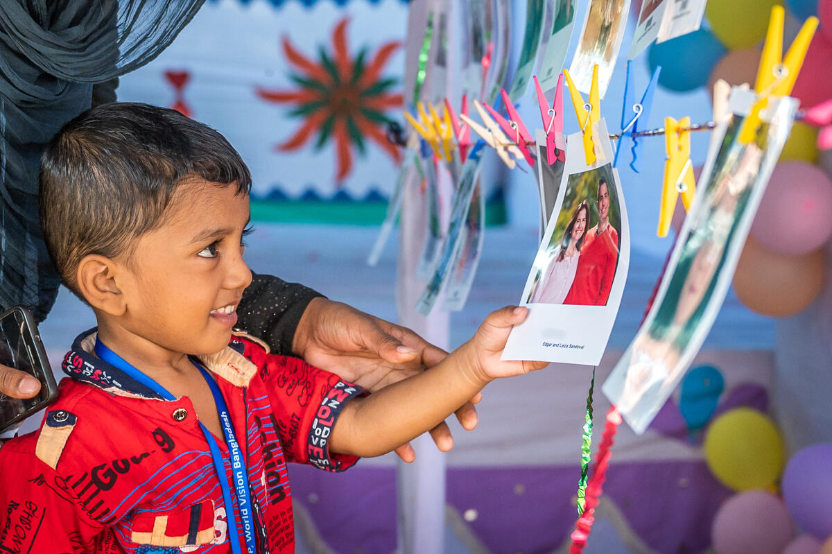 A young boy chooses the photo of who he wants to be sponsored by.