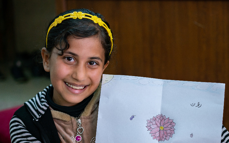 A girl showing her drawing to camera