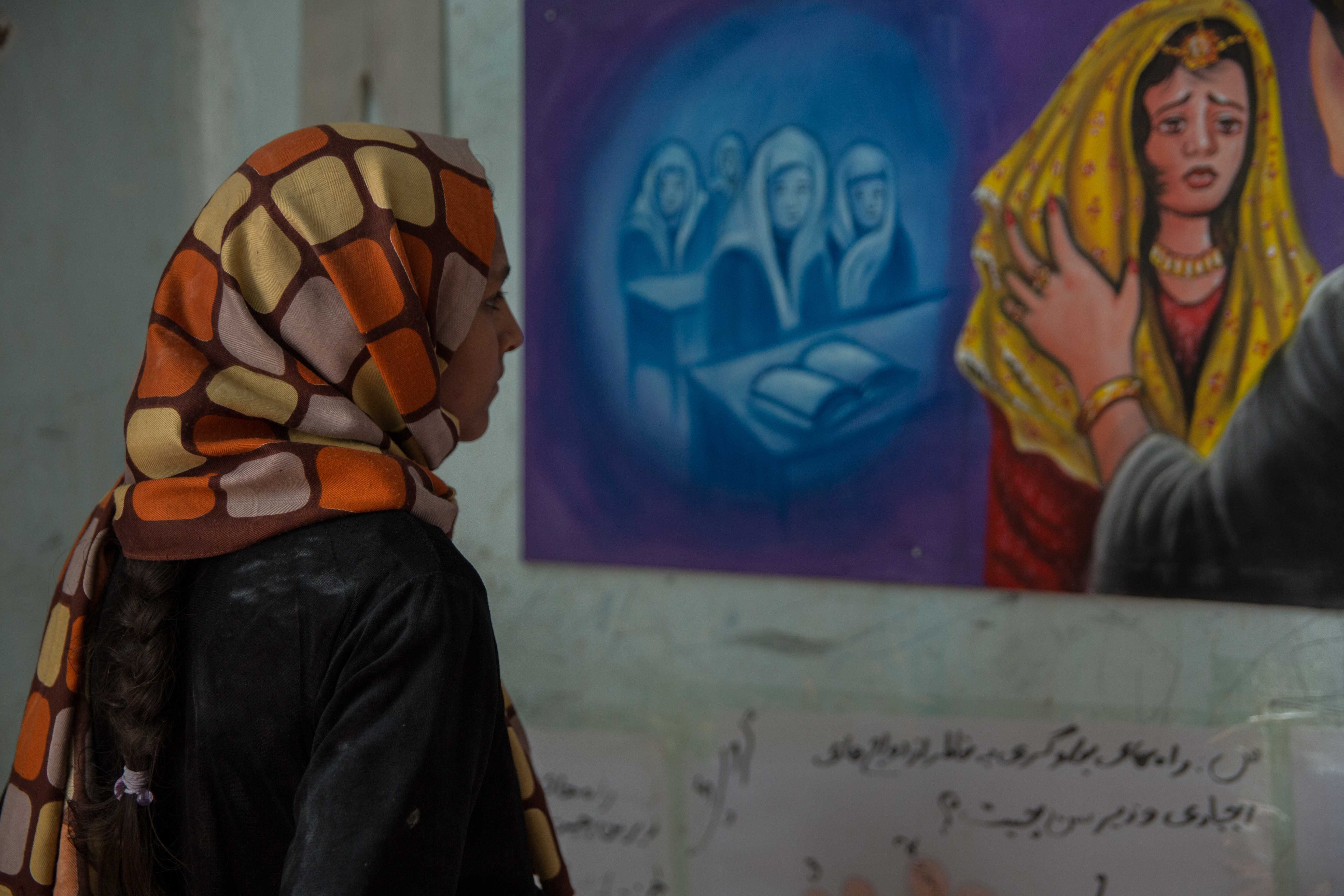 Girl in Afghanistan looks at an image of a woman