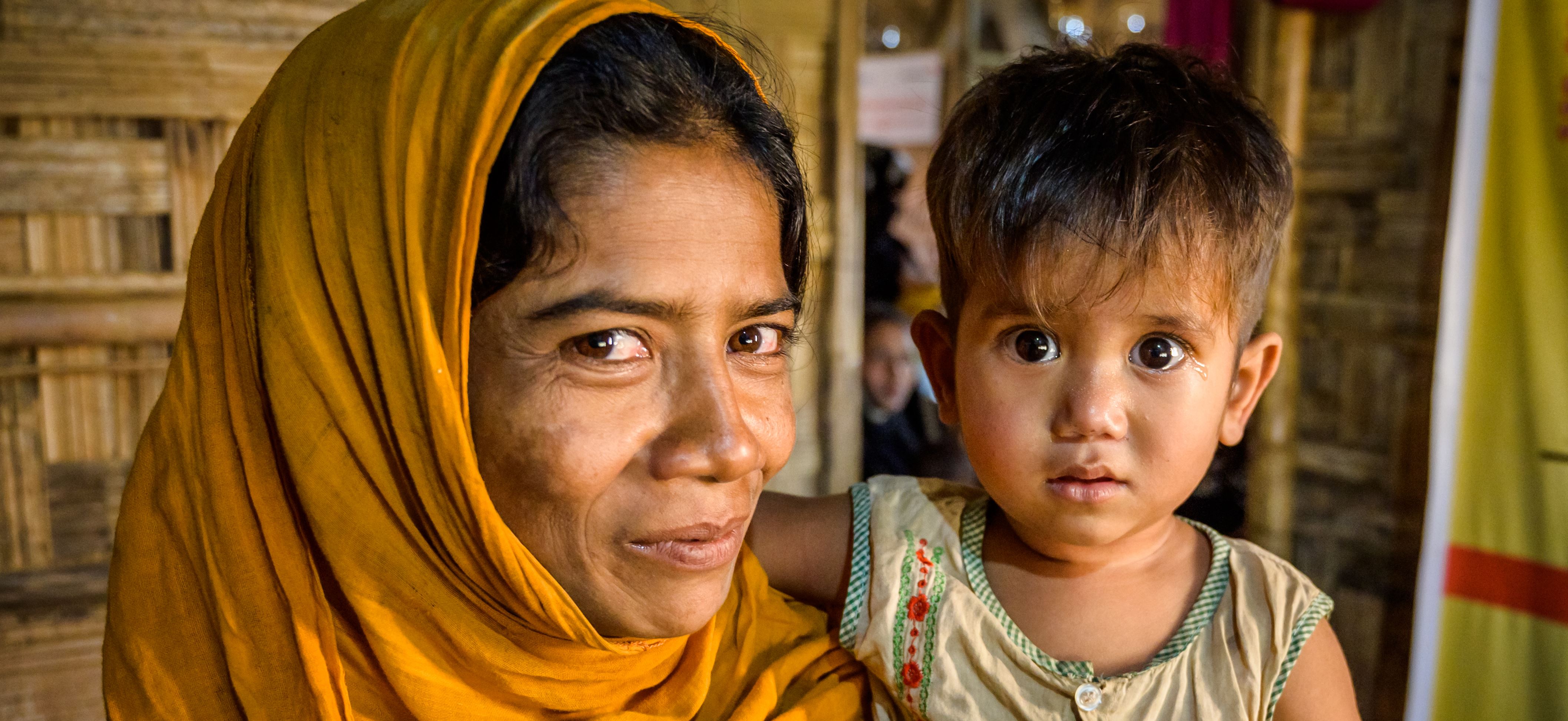 Mother and her child, Rohingya refugees, who fled to Bangladesh, look into the camera, happier now the child has recovered from malnutrition