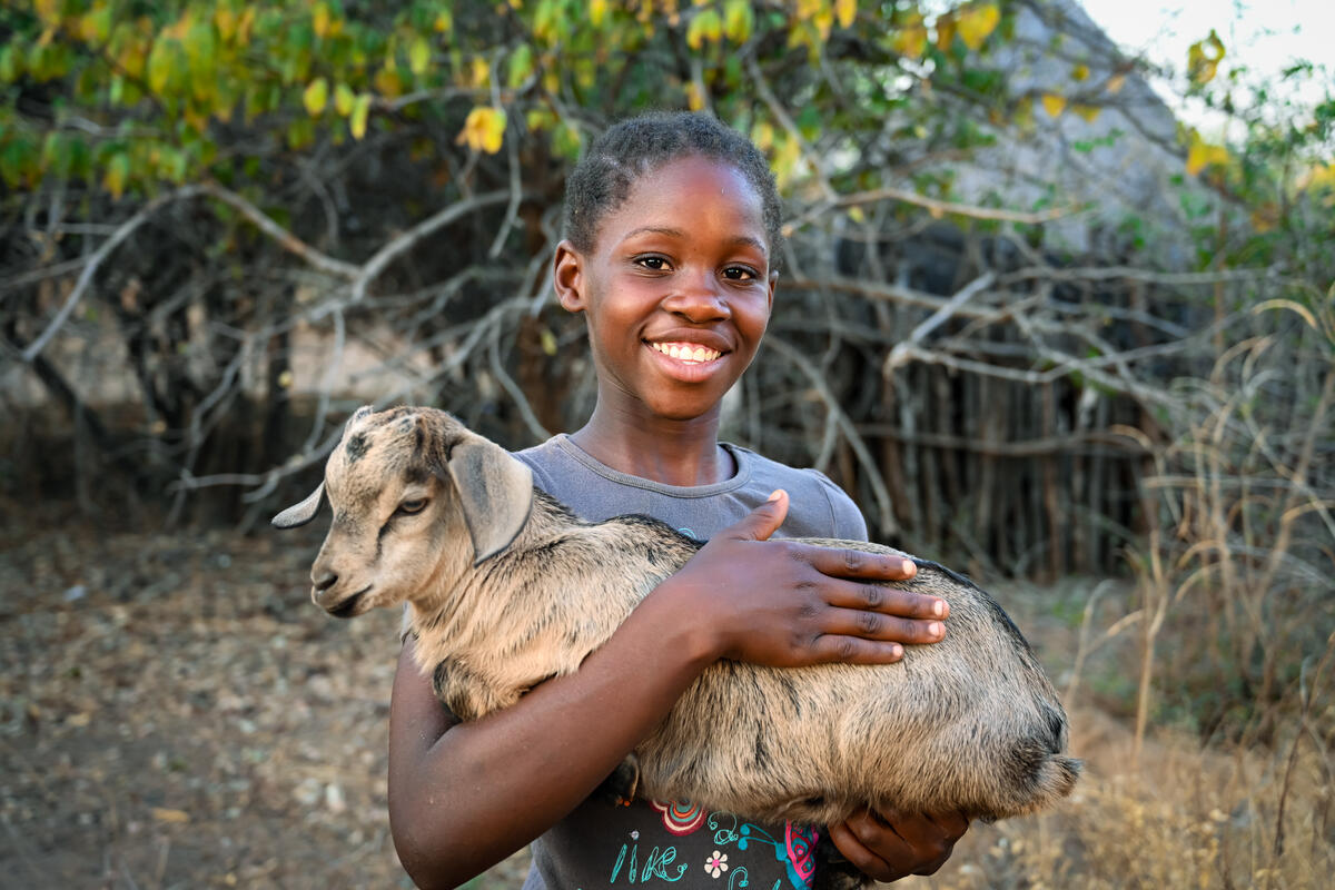 Girl smiling while holding a goat