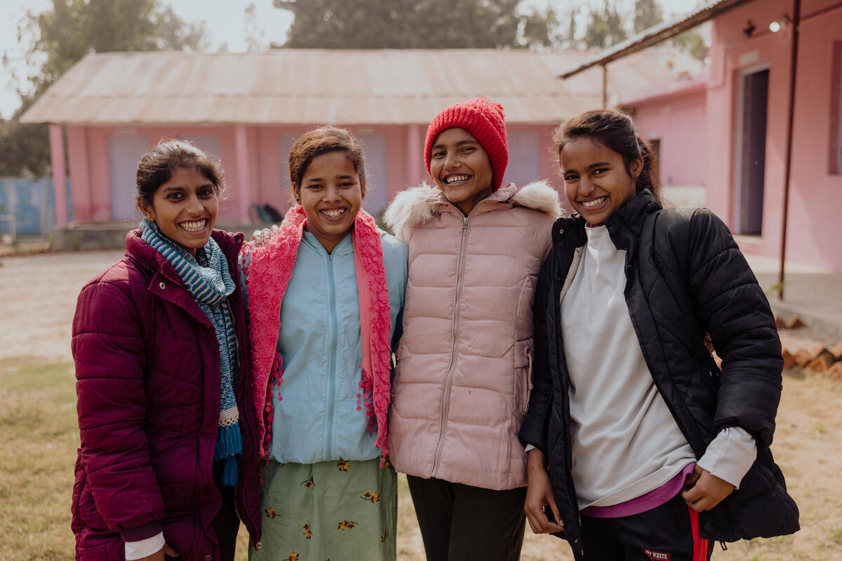 Four teenage girls in Nepal stand together smiling at the camera