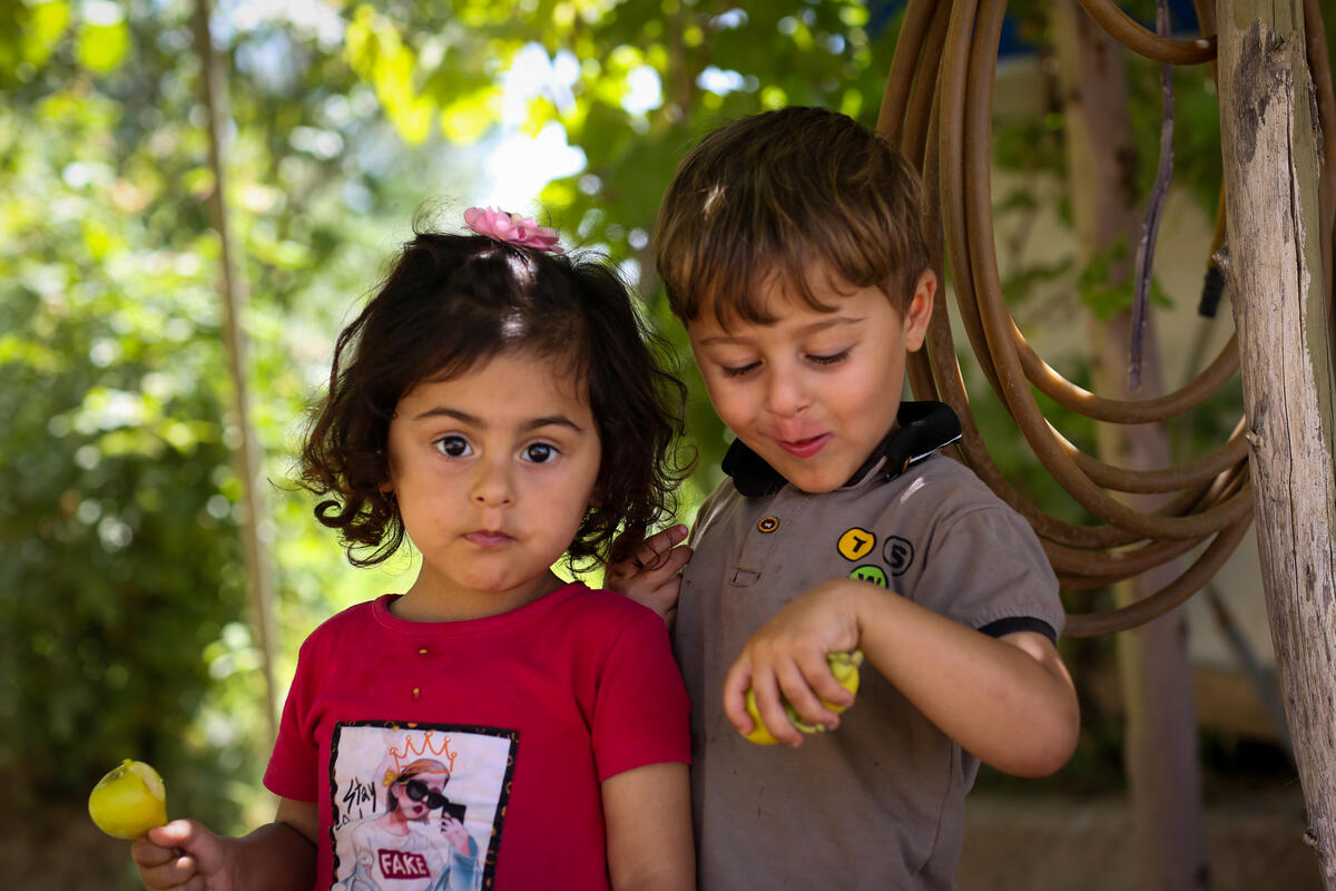 Young girl and boy from Iraq holding home grown crops