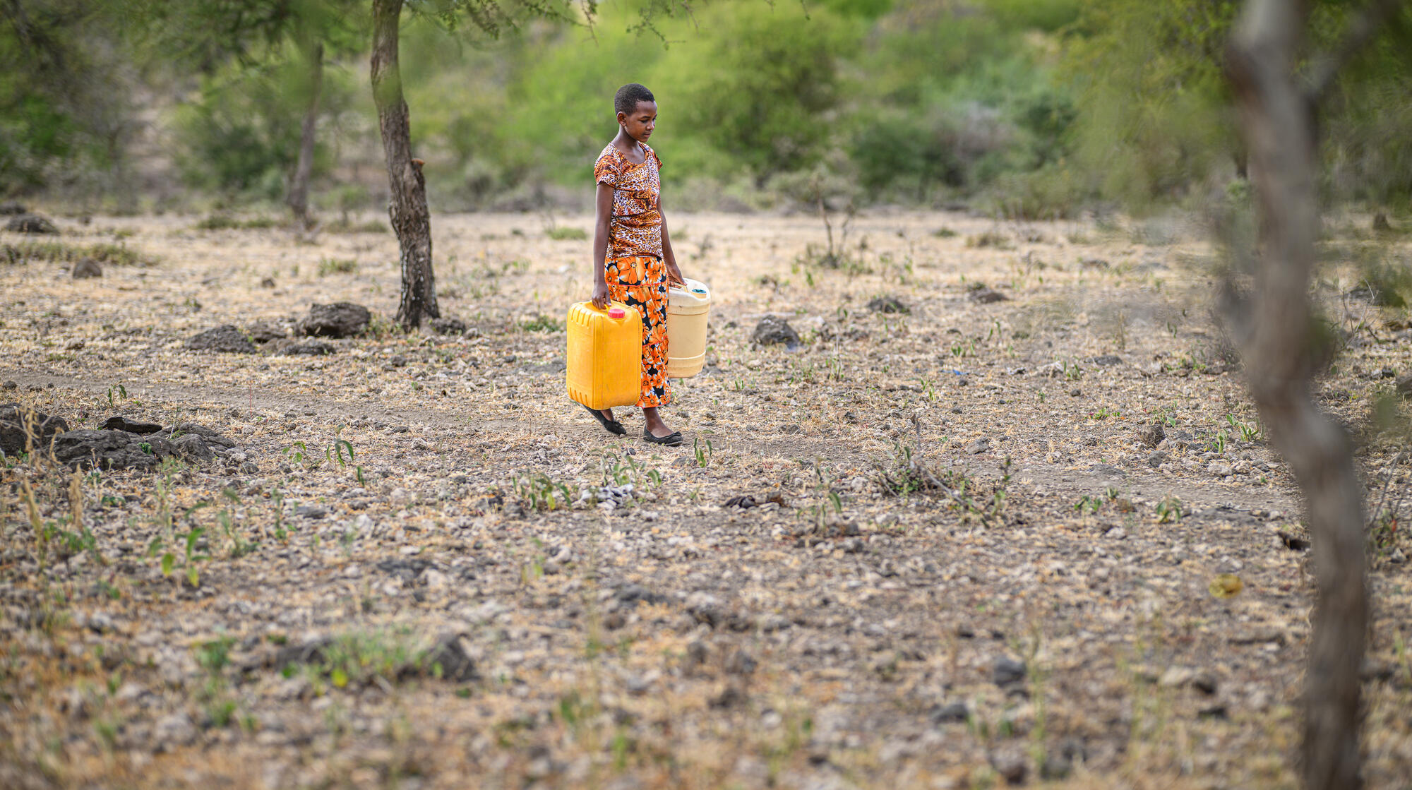 A girl in Tanzania stands in front of a dark background and soft white lights