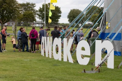 Awaken sign with people entering big tent