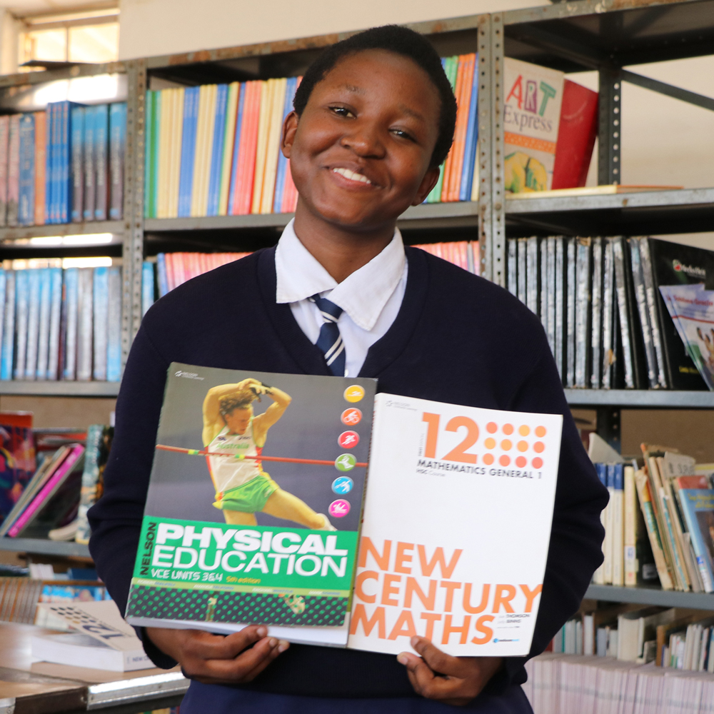 School child displaying books in library