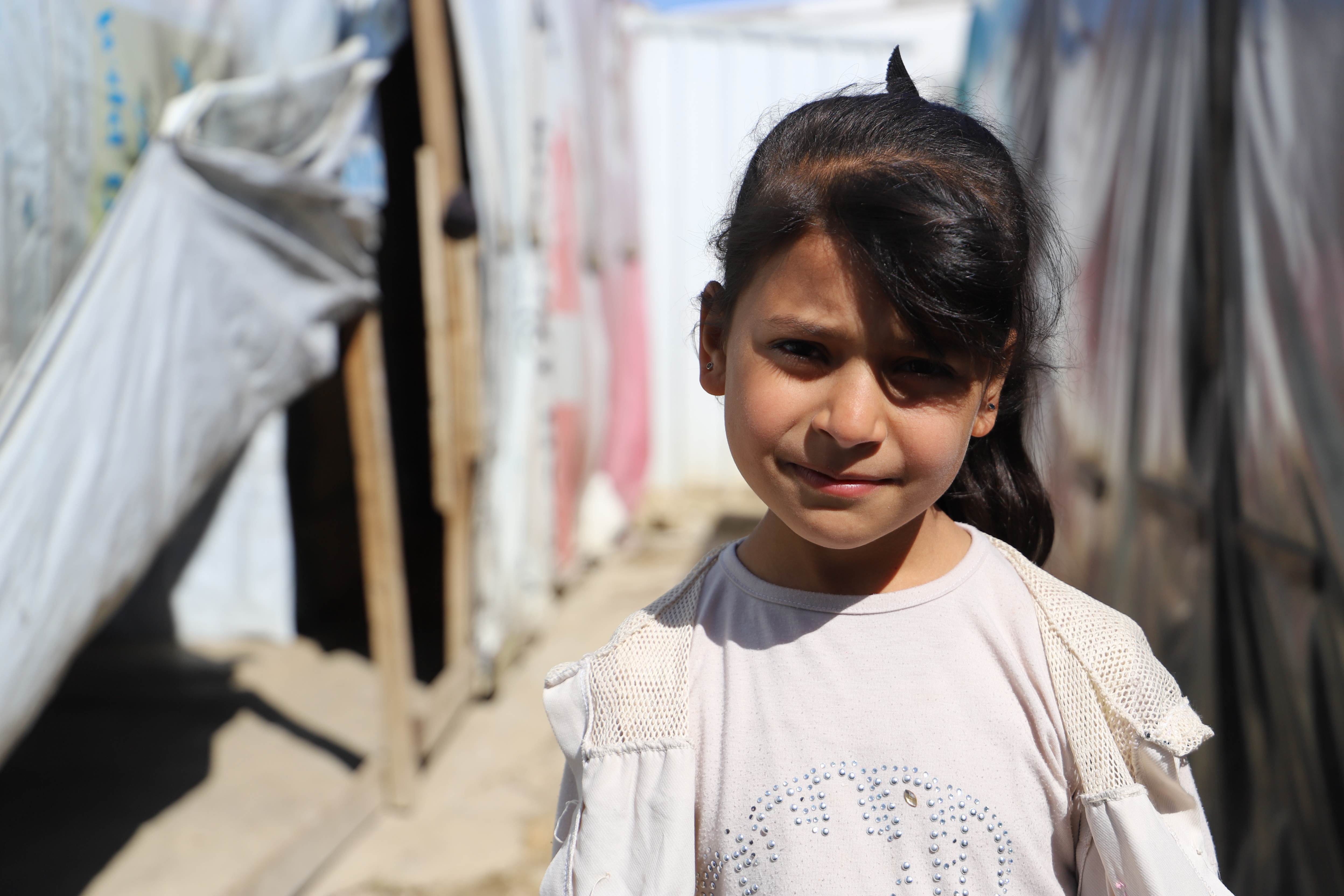 A girl from Syria stands between tents in a refugee settlement in Lebanon.